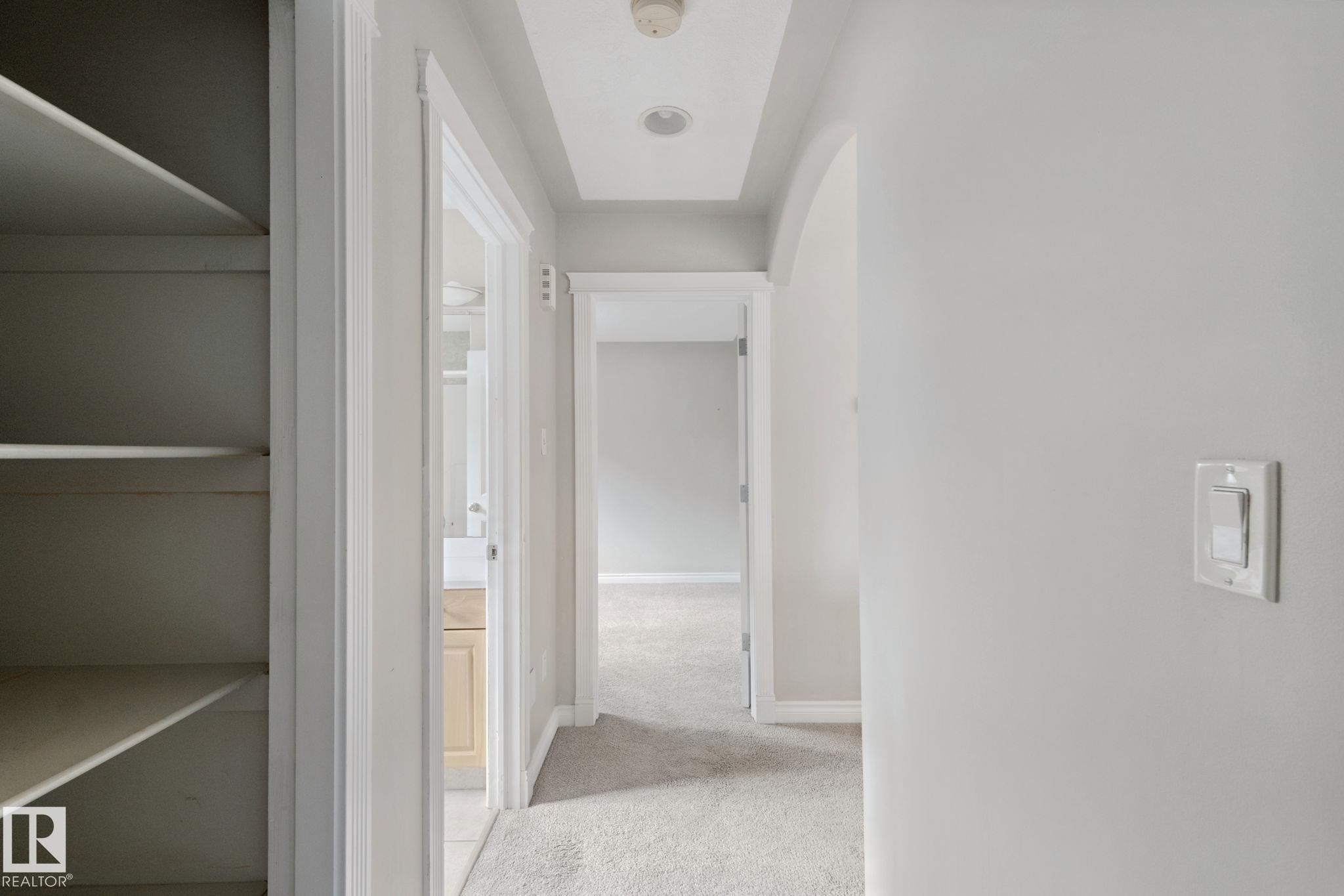 Hallway featuring recessed lighting, tray ceiling, built-in shelving, and neutral wall tones - 16807 78 Street Nw, Edmonton, AB