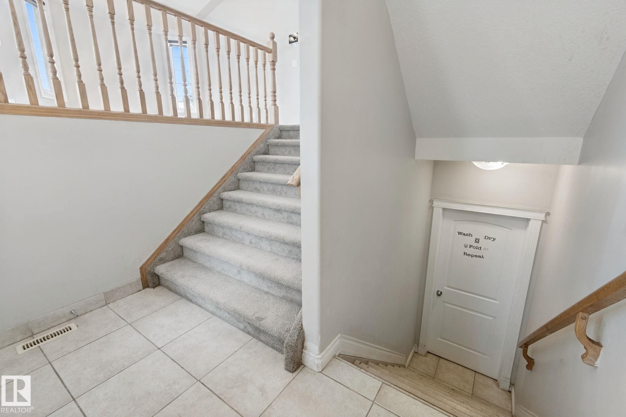 Staircase featuring carpeted treads, a light wood railing, and an upper landing with two windows - 16807 78 Street Nw, Edmonton, AB