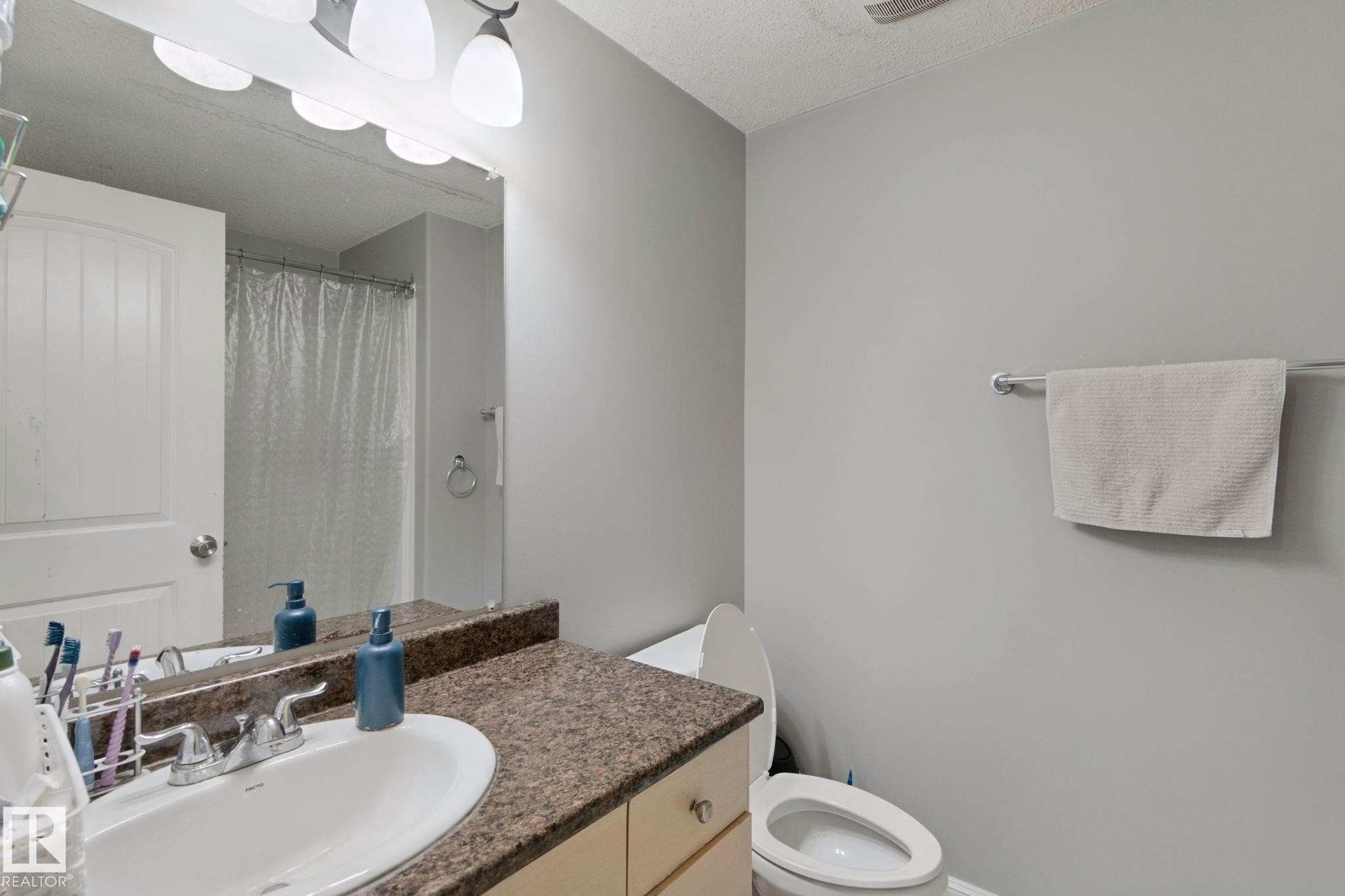 Vanity with a speckled countertop, integrated sink, and dual-handle faucet - 16807 78 Street Nw, Edmonton, AB