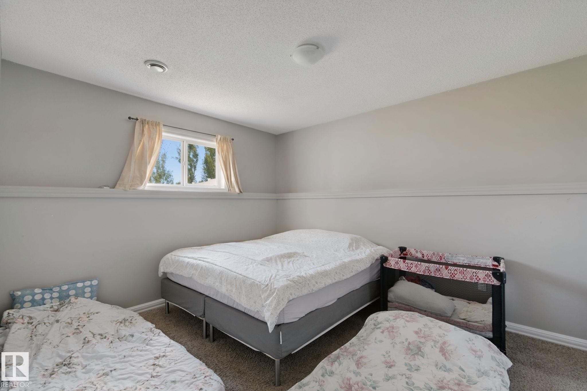 Wall-to-wall carpeting with a neutral finish, featuring a window with a valance and ceiling-mounted lighting - 16807 78 Street Nw, Edmonton, AB