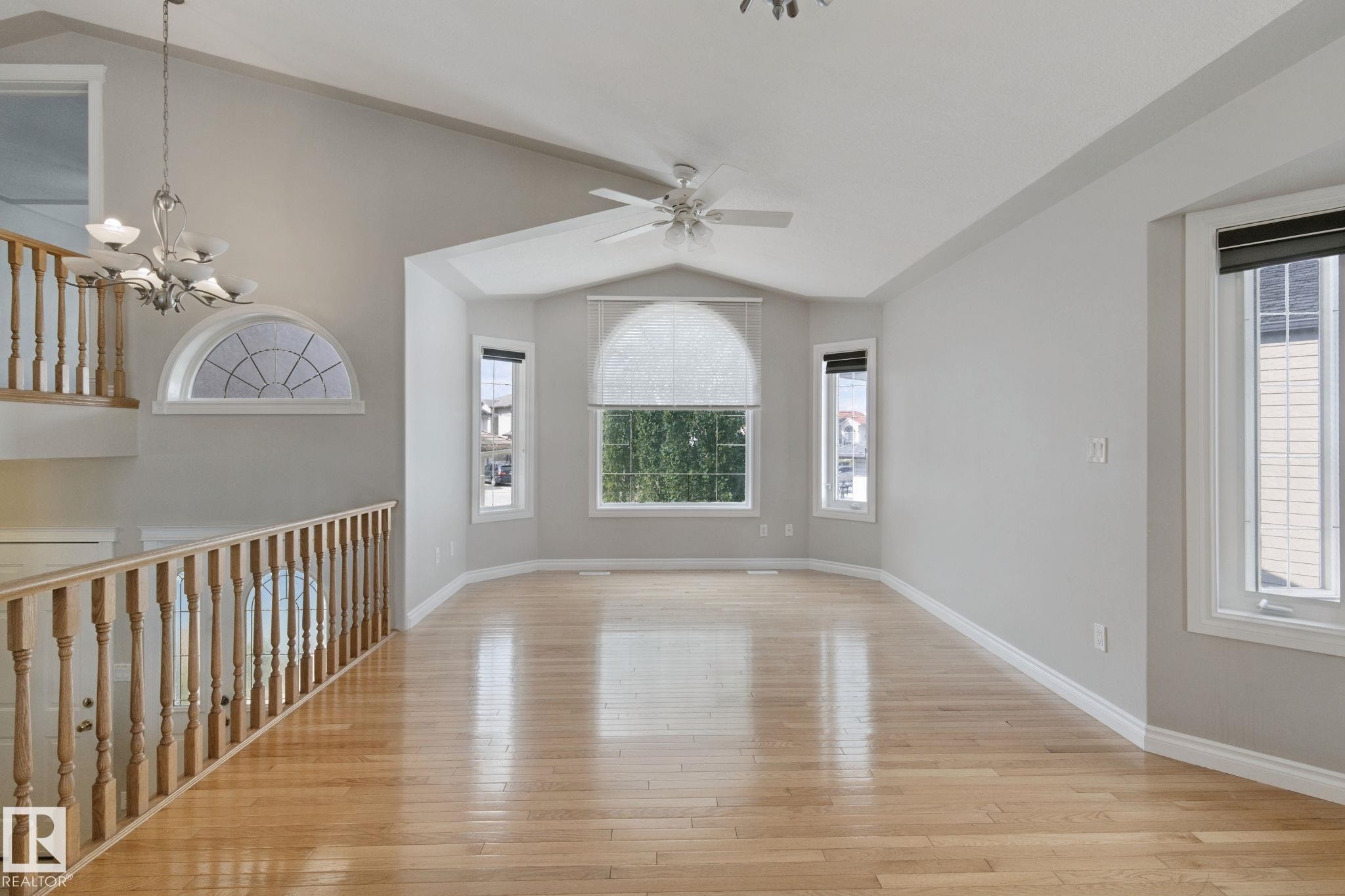 Vaulted ceiling with a ceiling fan, hardwood flooring, and a bay window - 16807 78 Street Nw, Edmonton, AB