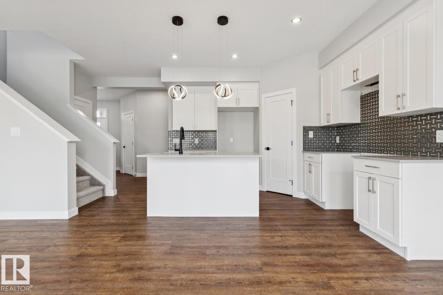 Open-concept kitchen with white cabinetry, a central island, and modern pendant lighting - 72 Maple Crescent, Gibbons, AB