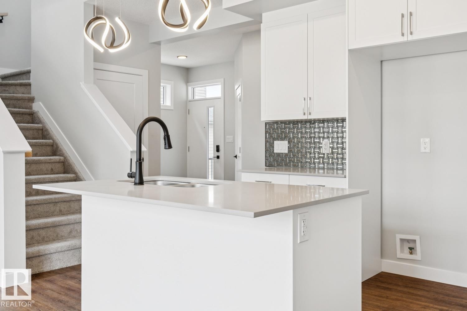 Kitchen island with integrated sink, quartz countertop, and matte black faucet - 72 Maple Crescent, Gibbons, AB