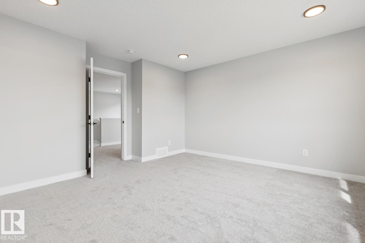 Recessed ceiling lighting, light gray wall paint, light gray carpeting, and white trim - 72 Maple Crescent, Gibbons, AB