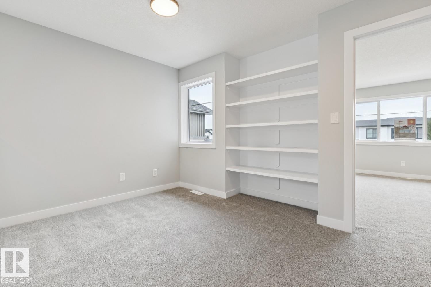 Recessed built-in shelving, light gray wall paint, light gray carpet, single window, and flush mount lighting - 72 Maple Crescent, Gibbons, AB