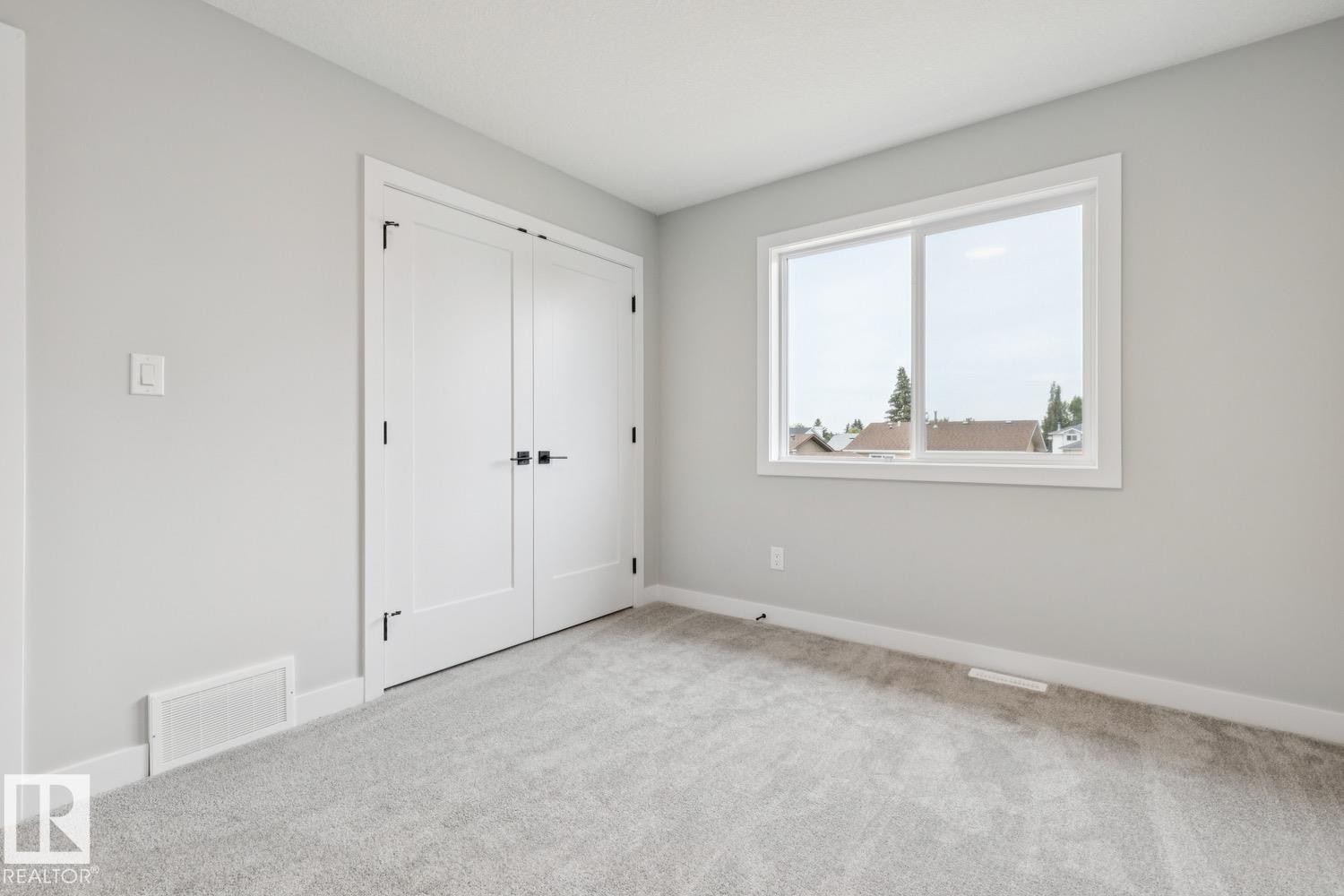 Soft gray wall finish, light gray carpet flooring, white trim, and a white framed window - 72 Maple Crescent, Gibbons, AB