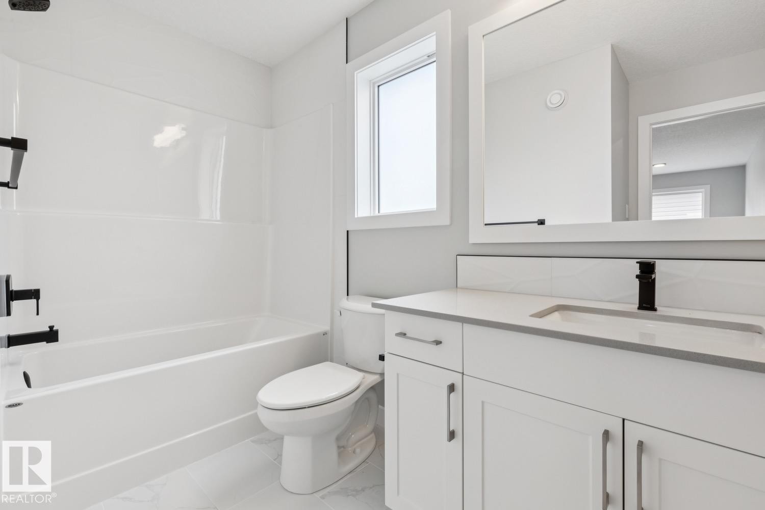 White vanity with a solid surface countertop, undermount sink, and matte black faucet - 72 Maple Crescent, Gibbons, AB
