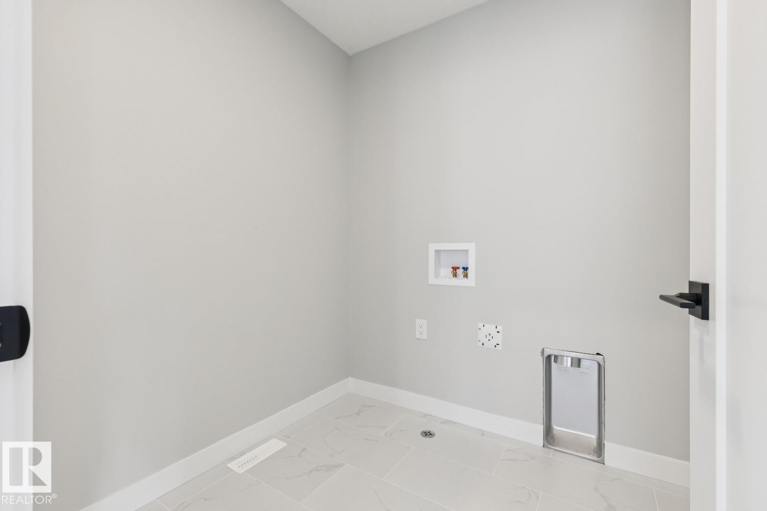 Laundry area with light-toned walls, tile flooring, and matte black hardware - 72 Maple Crescent, Gibbons, AB