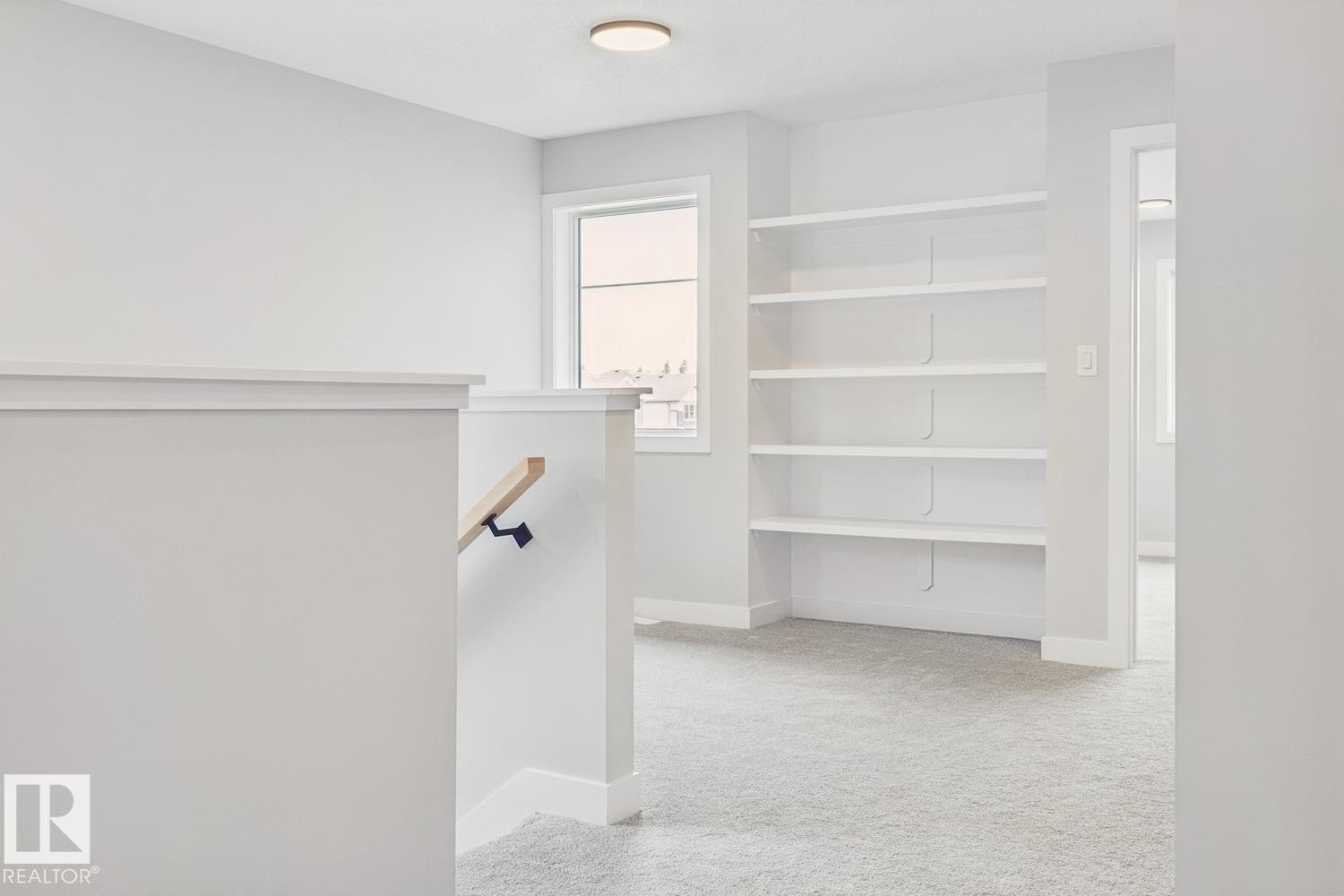 Built-in shelving, natural wood handrail, recessed ceiling light, and light-toned carpeting - 72 Maple Crescent, Gibbons, AB