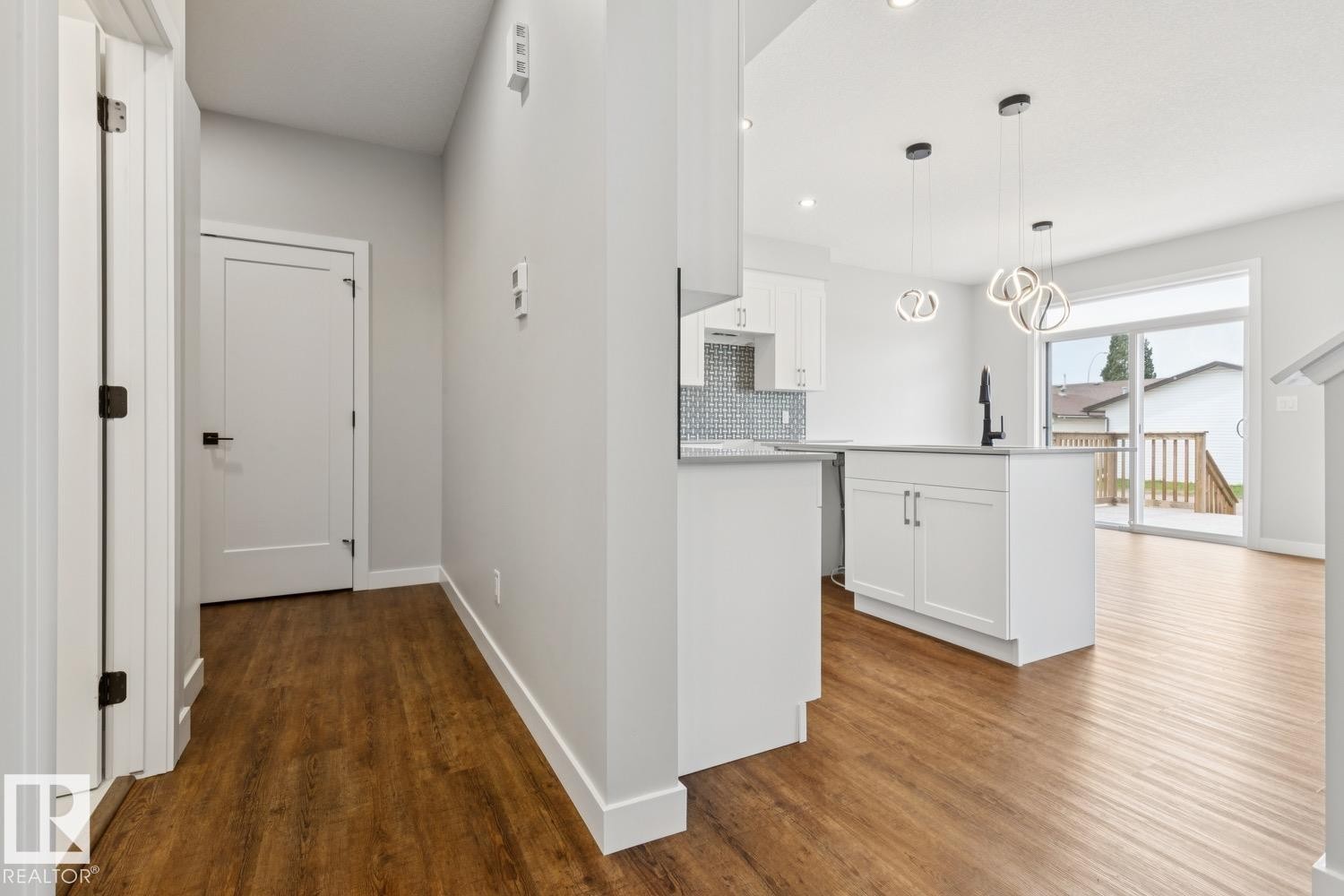 Kitchen featuring white cabinetry, a kitchen island, and a tile backsplash - 72 Maple Crescent, Gibbons, AB