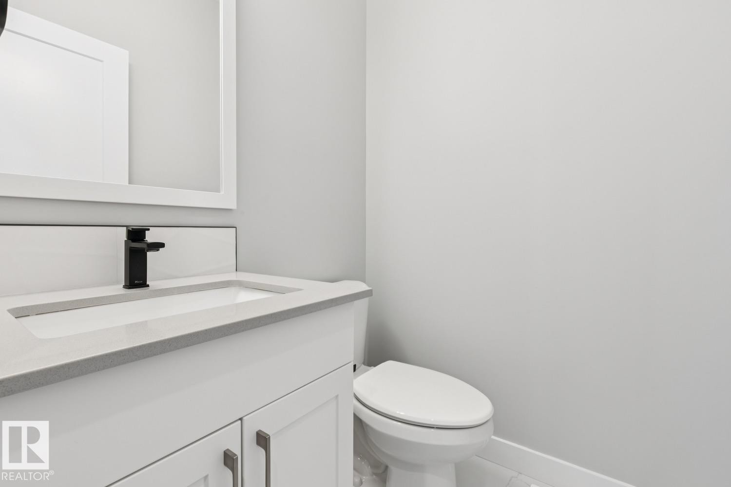 White vanity with a light-toned countertop, integrated rectangular sink, and matte black faucet - 72 Maple Crescent, Gibbons, AB