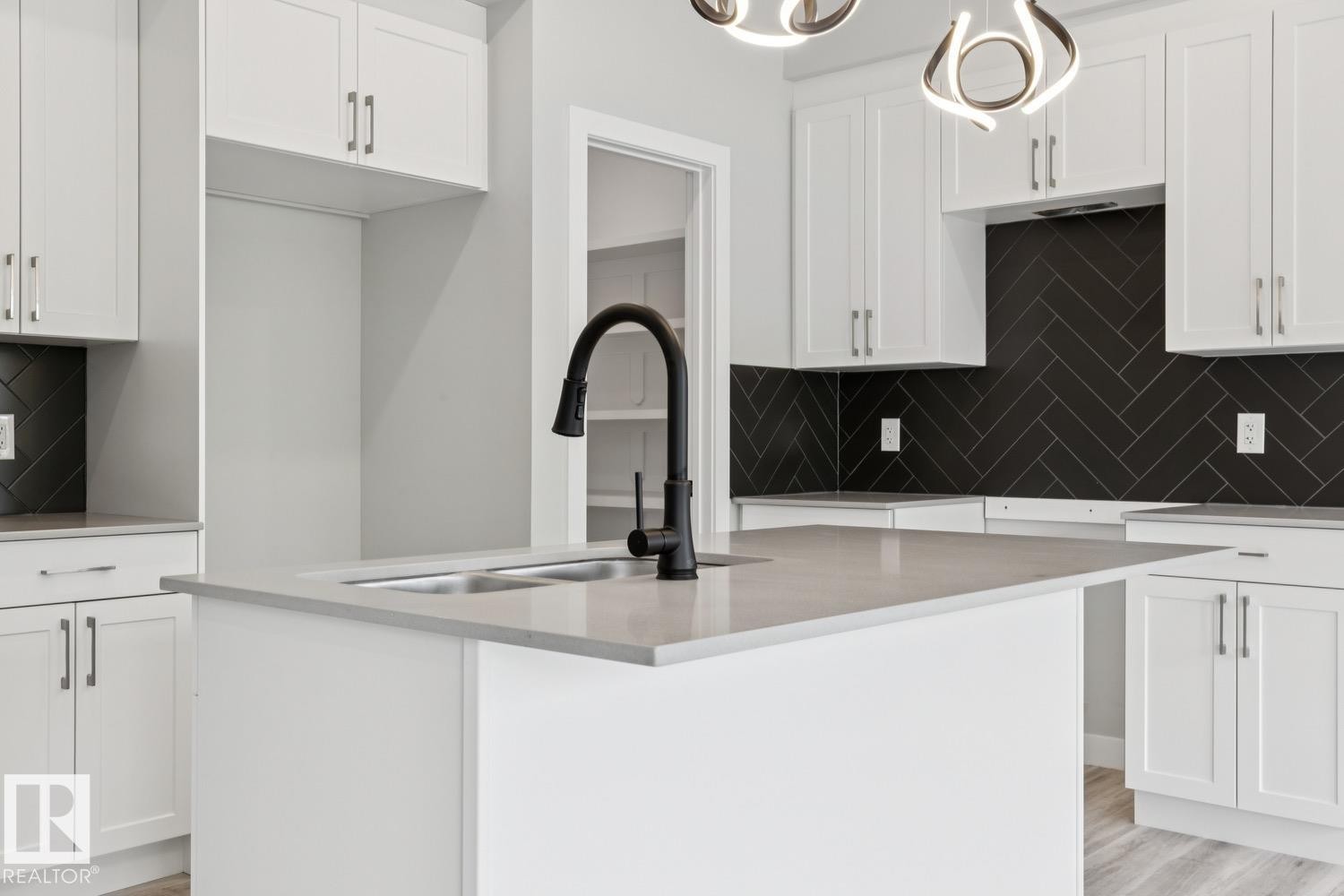 White shaker cabinetry, light-toned countertops, black herringbone tile backsplash, and a matte black gooseneck faucet - 36 Maple Crescent, Gibbons, AB