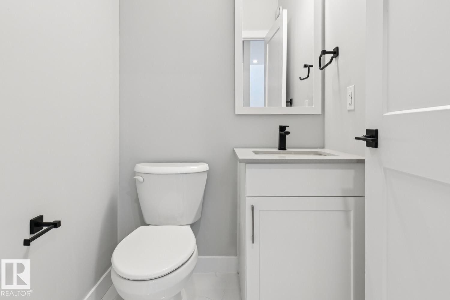 White vanity with a rectangular sink, black faucet, and coordinating mirror - 36 Maple Crescent, Gibbons, AB