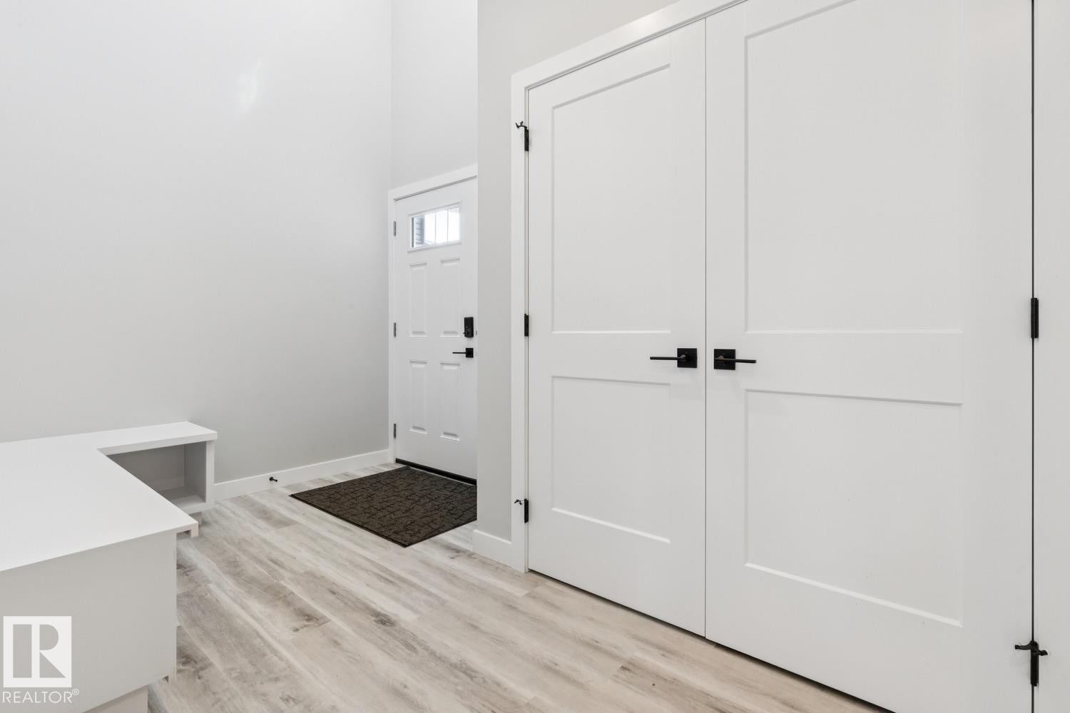 High ceilings, wood-finish flooring, built-in bench seating, white paneled doors, and black hardware accents - 36 Maple Crescent, Gibbons, AB