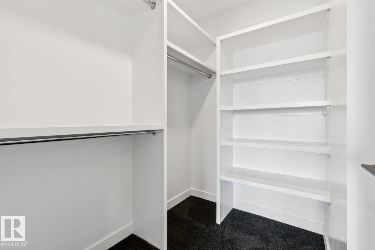 Built-in closet organization featuring multiple shelving units, integrated hanging rods, and dark carpeting - 36 Maple Crescent, Gibbons, AB