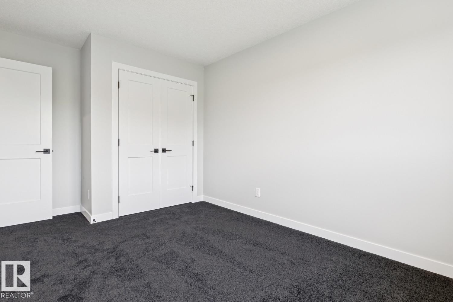 Bright bedroom with clean white walls, dark carpet flooring, and abundant natural light from overhead fixtures - 36 Maple Crescent, Gibbons, AB