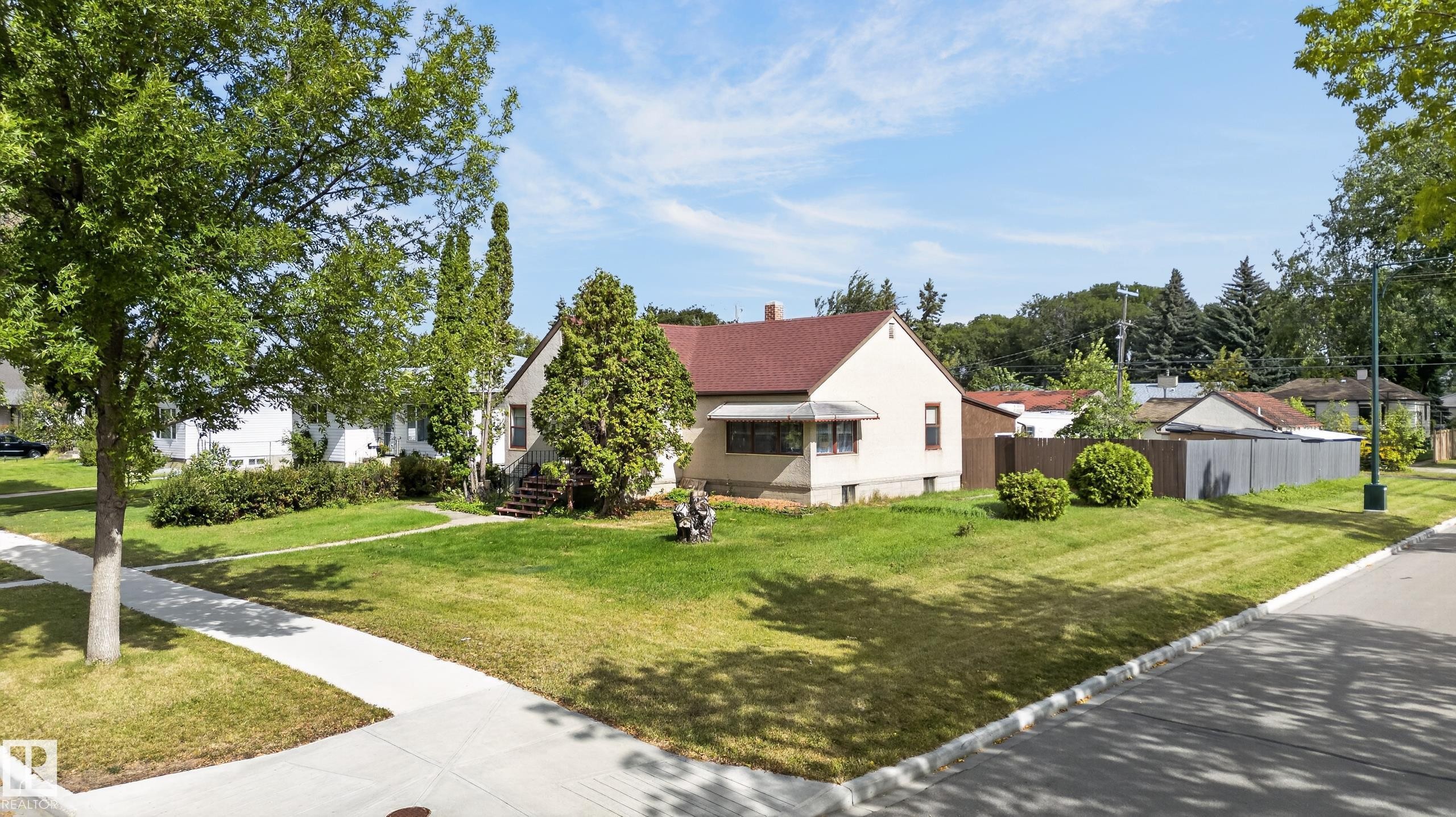 Corner lot property featuring mature trees, a red shingle roof, a light-toned exterior, and a well-maintained lawn - 12309 80 Street Nw, Edmonton, AB