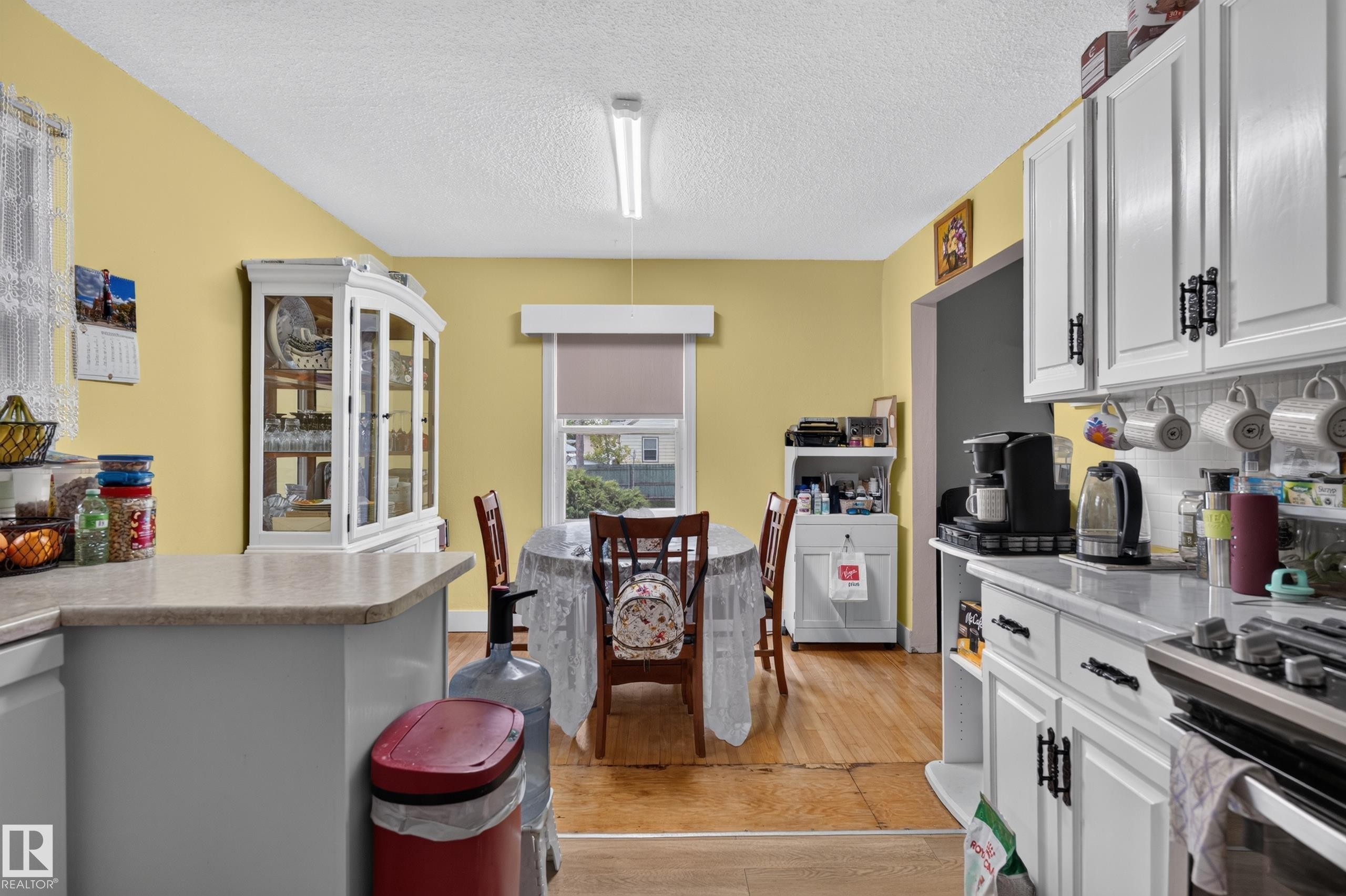 Well-appointed kitchen featuring white cabinetry with black hardware, light-colored countertops, and hardwood-finish flooring - 12309 80 Street Nw, Edmonton, AB