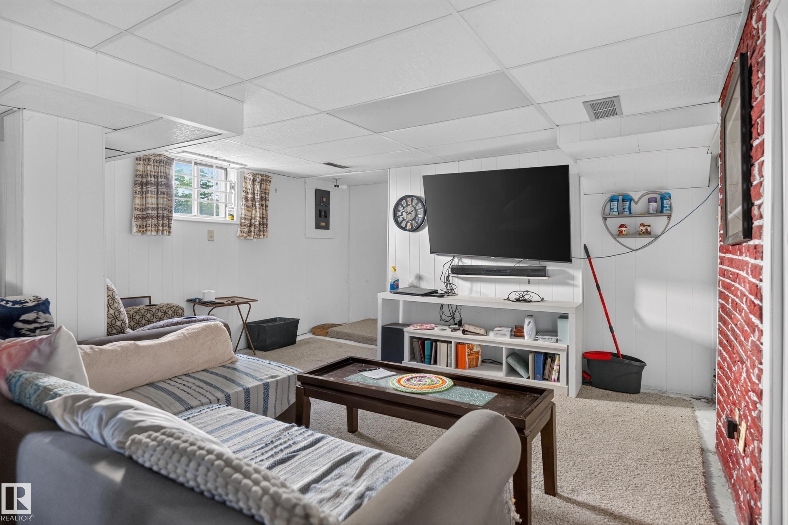 Paneled walls, drop ceiling, carpeted flooring, built-in shelving, and exposed brick-finish wall - 12309 80 Street Nw, Edmonton, AB