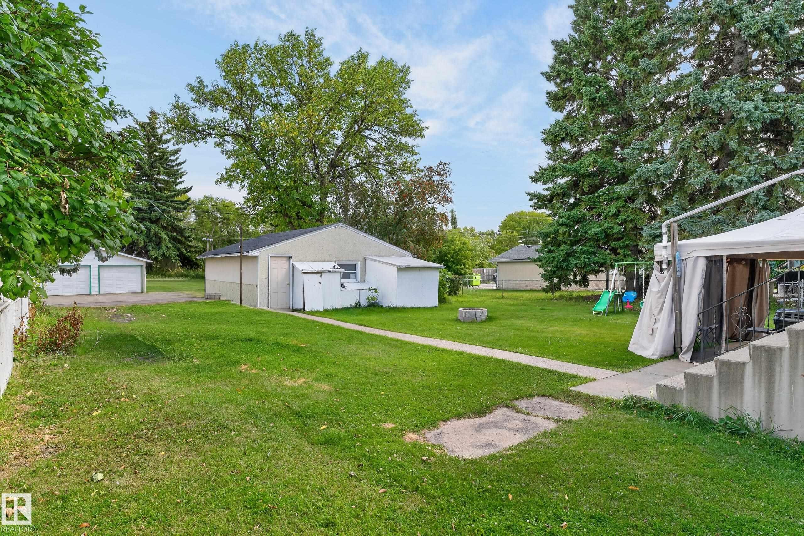 Expansive green lawn with mature trees and a detached garage featuring two roll-up doors - 12345 79 Street Nw, Edmonton, AB