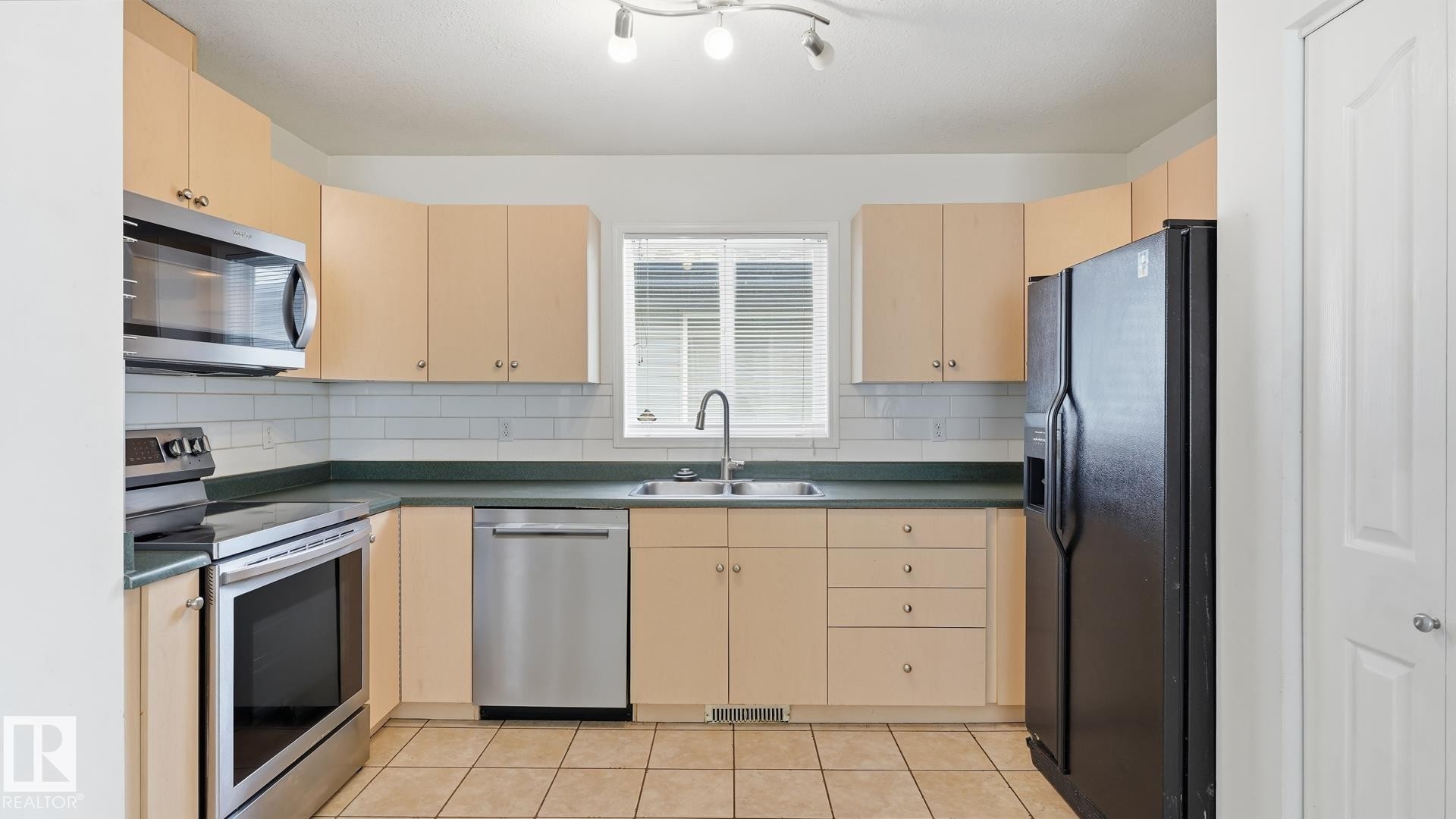 Kitchen with light-toned cabinetry, tile flooring, and a subway tile backsplash - 2117 36 Avenue Nw, Edmonton, AB