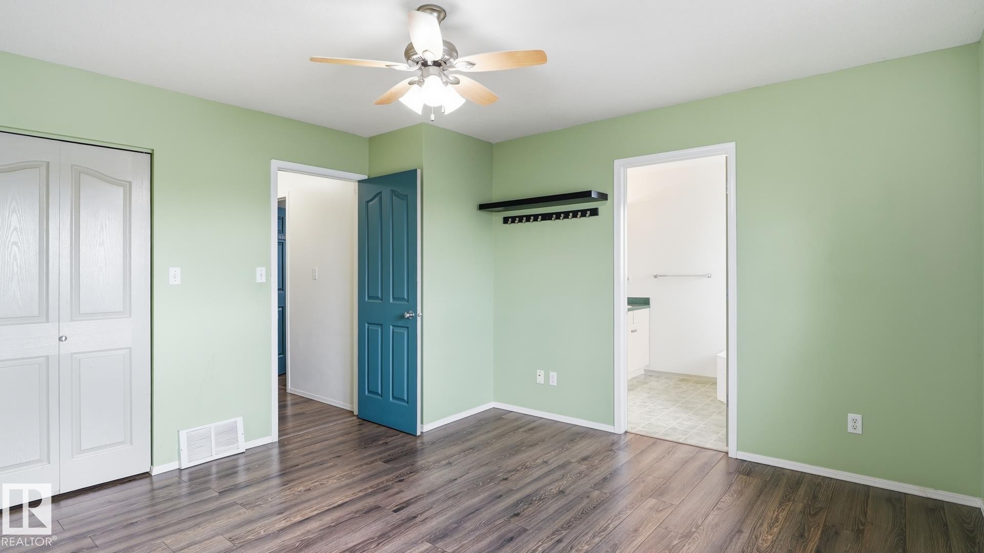 Wood-finish flooring with a ceiling fan light fixture, white bi-fold closet doors, and a built-in wall shelf with hooks - 2117 36 Avenue Nw, Edmonton, AB