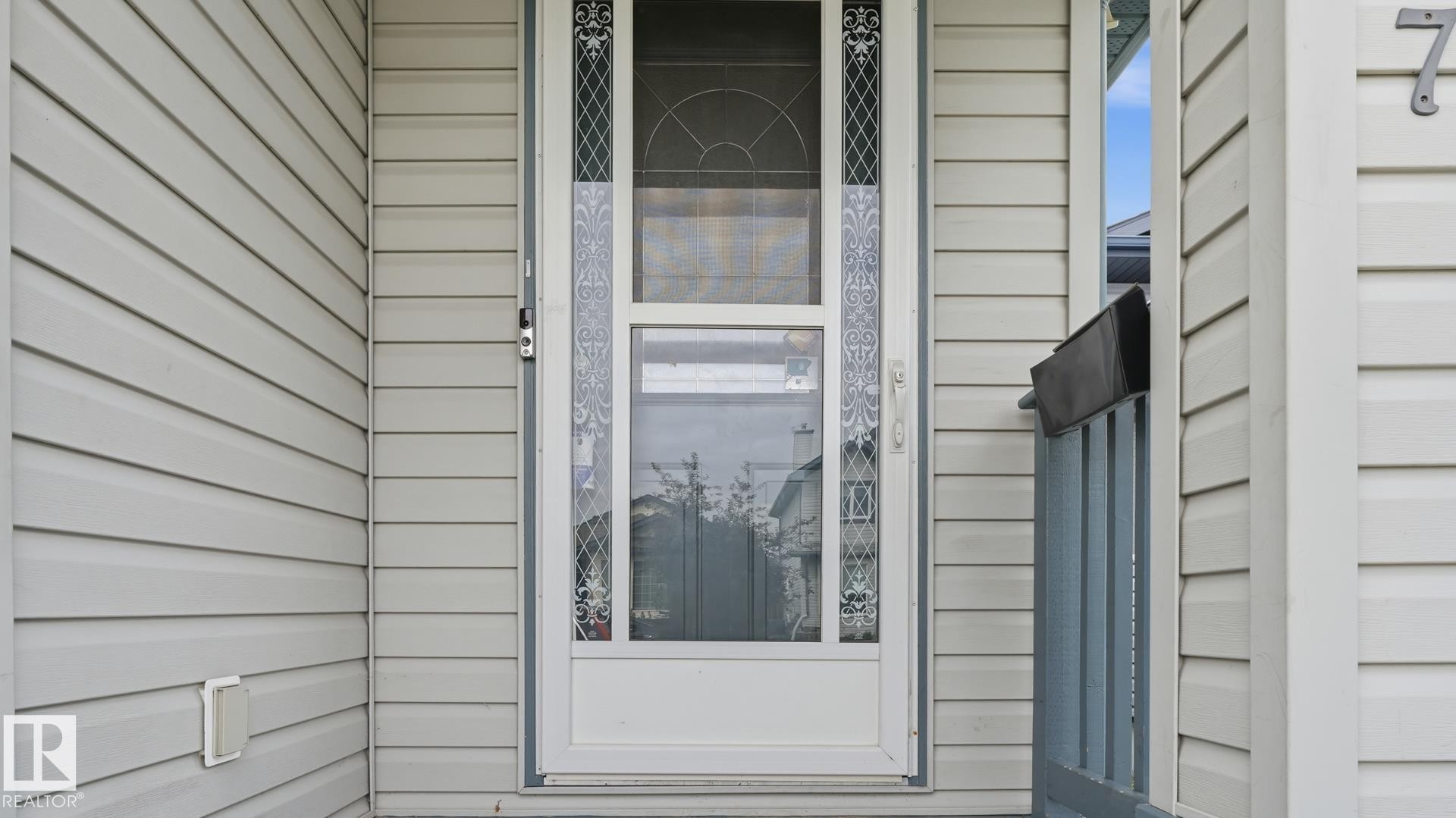 Front entry with decorative glass storm door and light-toned horizontal siding - 2117 36 Avenue Nw, Edmonton, AB