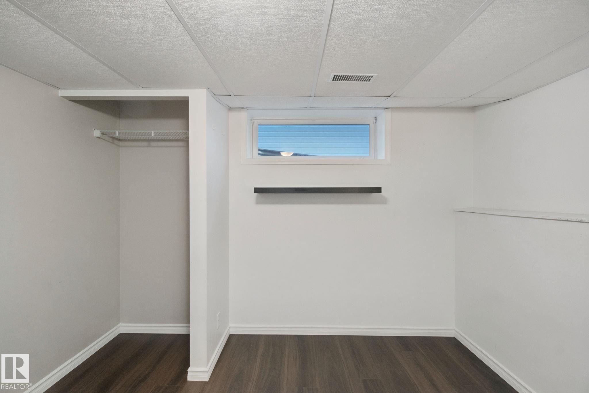Recessed window, wood-finish flooring, drop-tile ceiling, built-in shelving, and closet rod - 2117 36 Avenue Nw, Edmonton, AB
