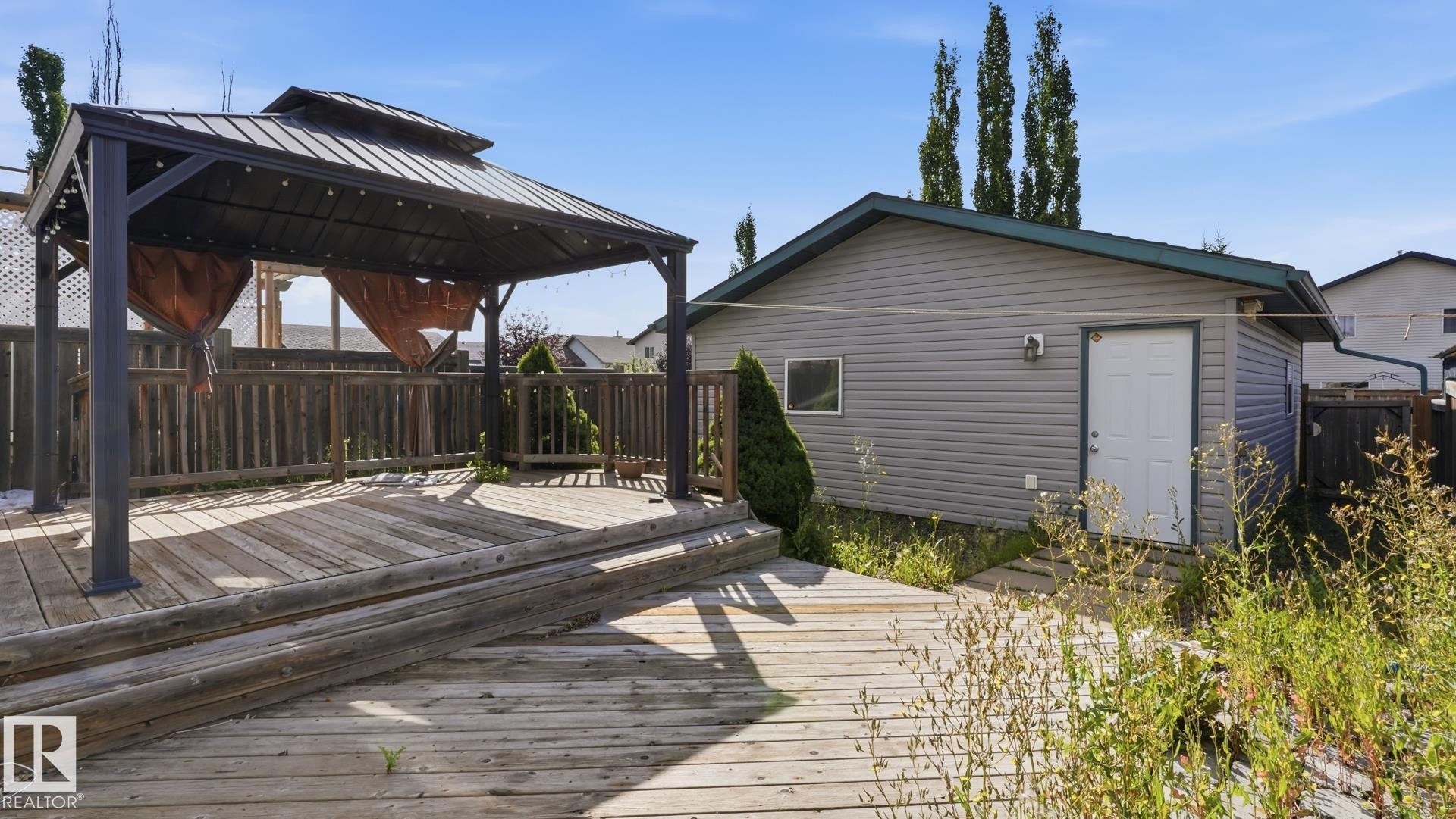 Multi-level wood-finish deck featuring a metal-frame gazebo - 2117 36 Avenue Nw, Edmonton, AB