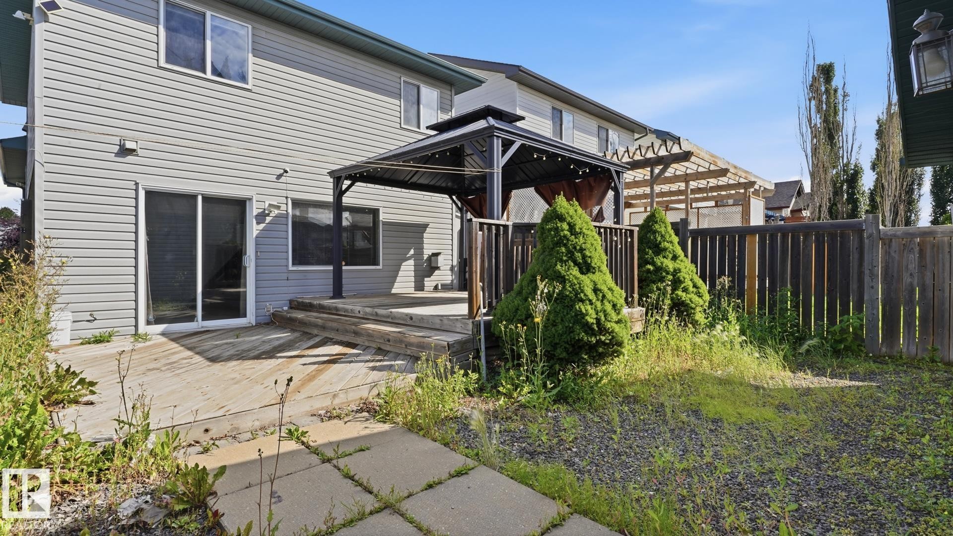 Rear exterior with horizontal siding, sliding glass door, multi-level wood deck, and a detached gazebo - 2117 36 Avenue Nw, Edmonton, AB