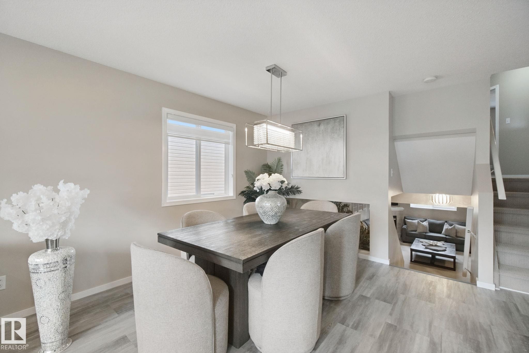 Recessed lighting, wood-finish flooring, and a contemporary linear chandelier illuminate this dining area - 13912 156 Avenue Nw, Edmonton, AB