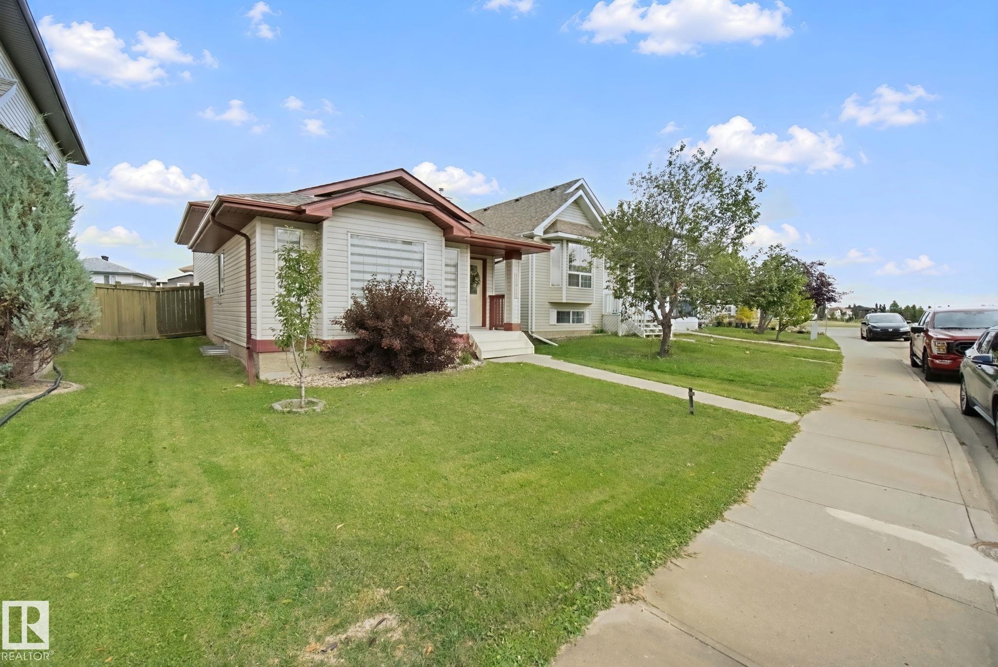 Manicured front lawn with a concrete walkway and mature shrubbery - 13912 156 Avenue Nw, Edmonton, AB