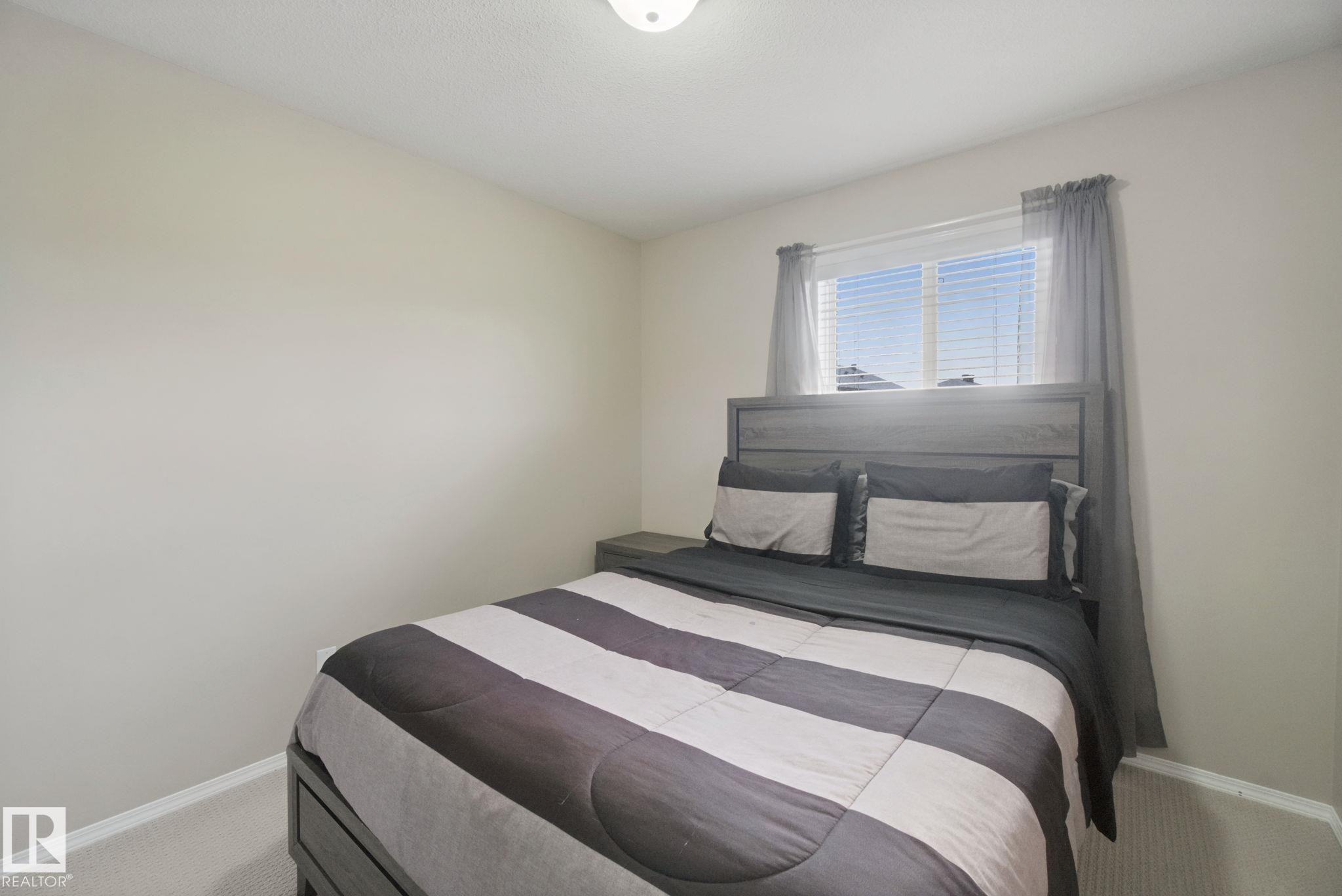 Neutral wall paint, ceiling-mounted light fixture, window with blinds, and light-toned carpeting - 13912 156 Avenue Nw, Edmonton, AB