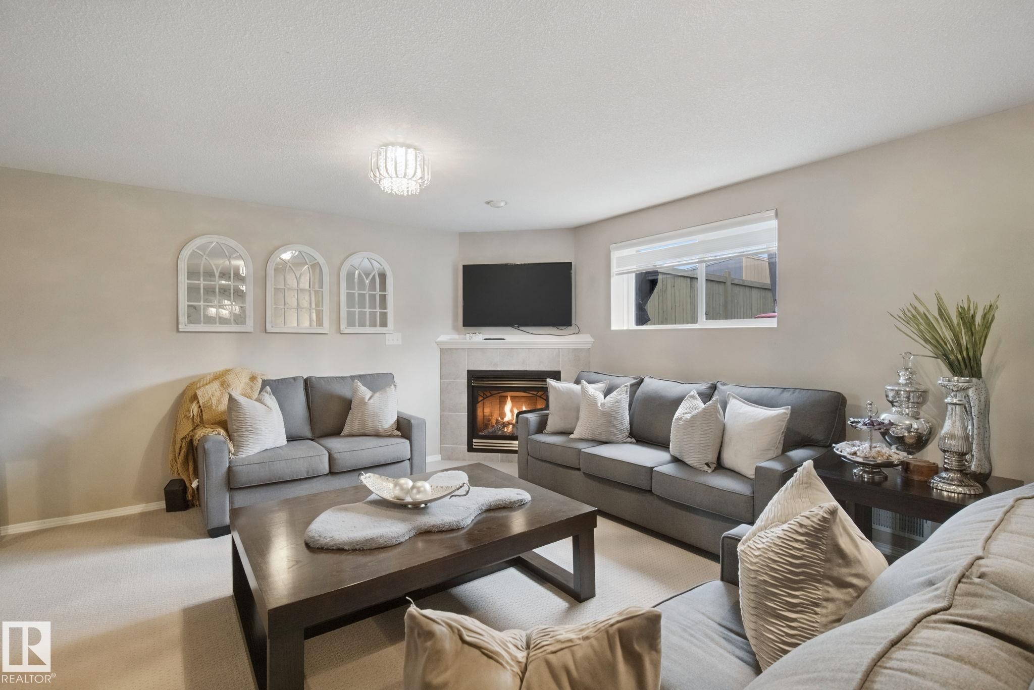 Corner fireplace with tile surround, a large window, and recessed lighting - 13912 156 Avenue Nw, Edmonton, AB