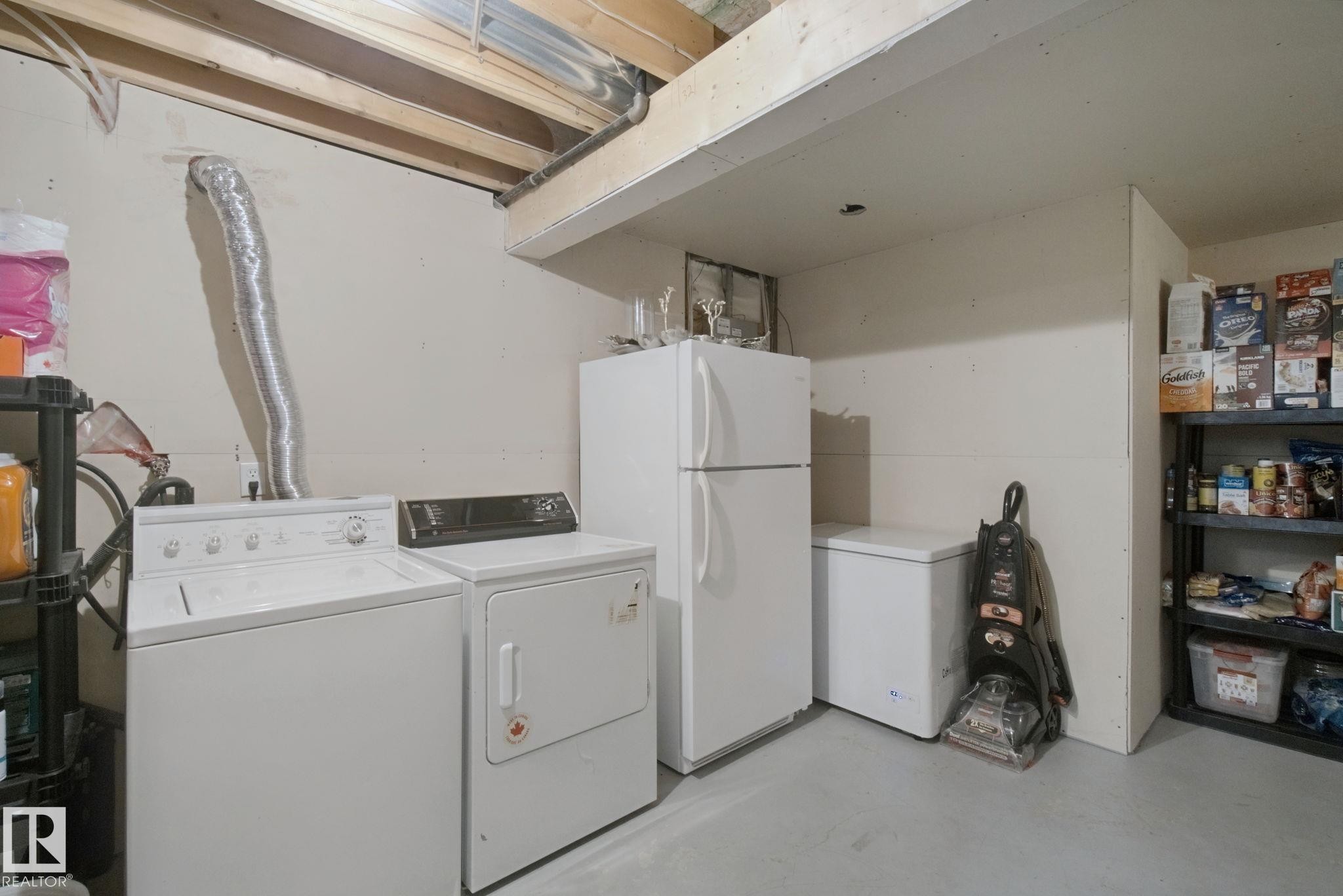 Laundry area featuring a washer and dryer, exposed ceiling joists, and a concrete floor - 13912 156 Avenue Nw, Edmonton, AB