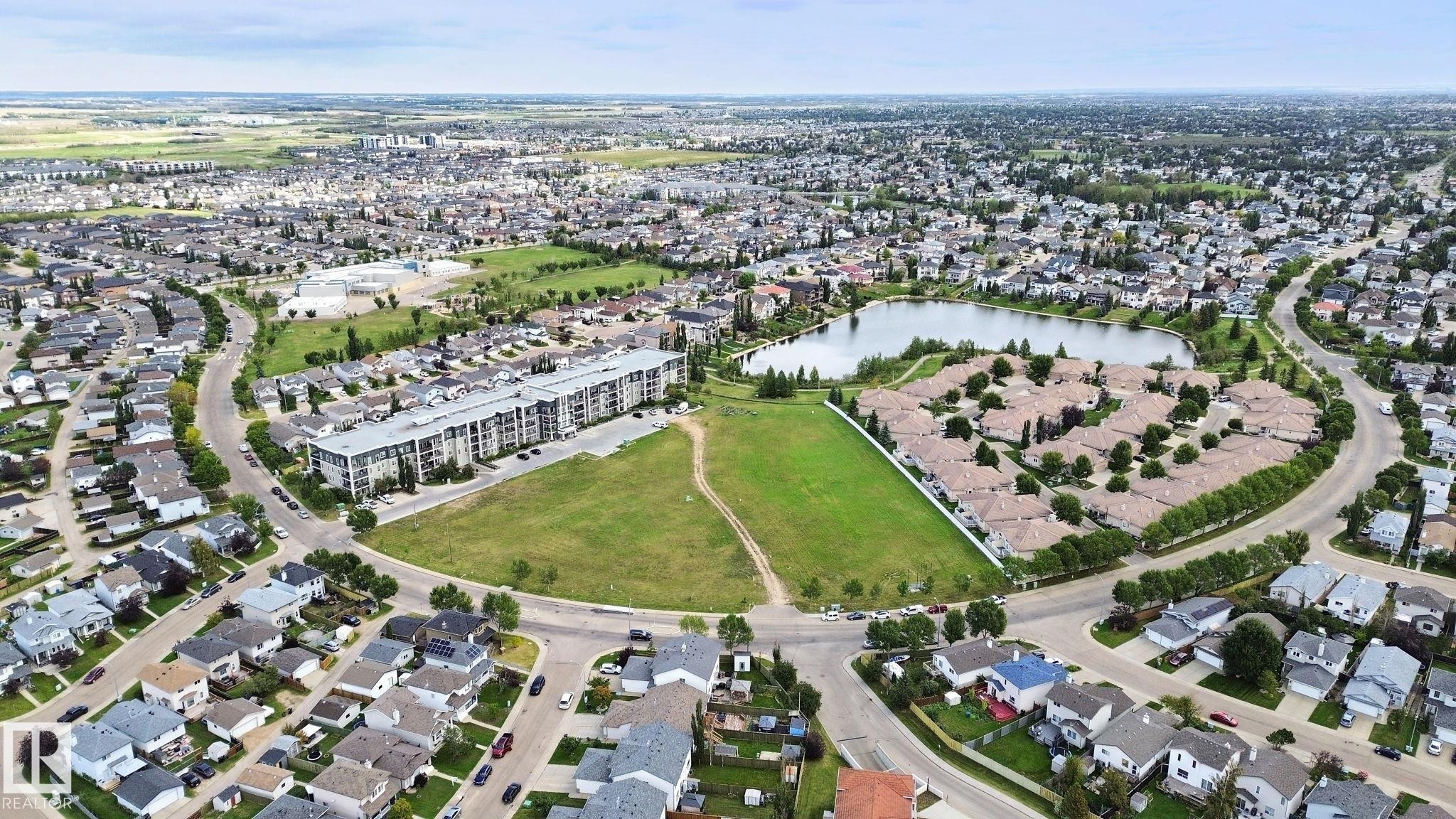 Aerial perspective showcasing a residential community, a central water feature, and surrounding green spaces - 13912 156 Avenue Nw, Edmonton, AB