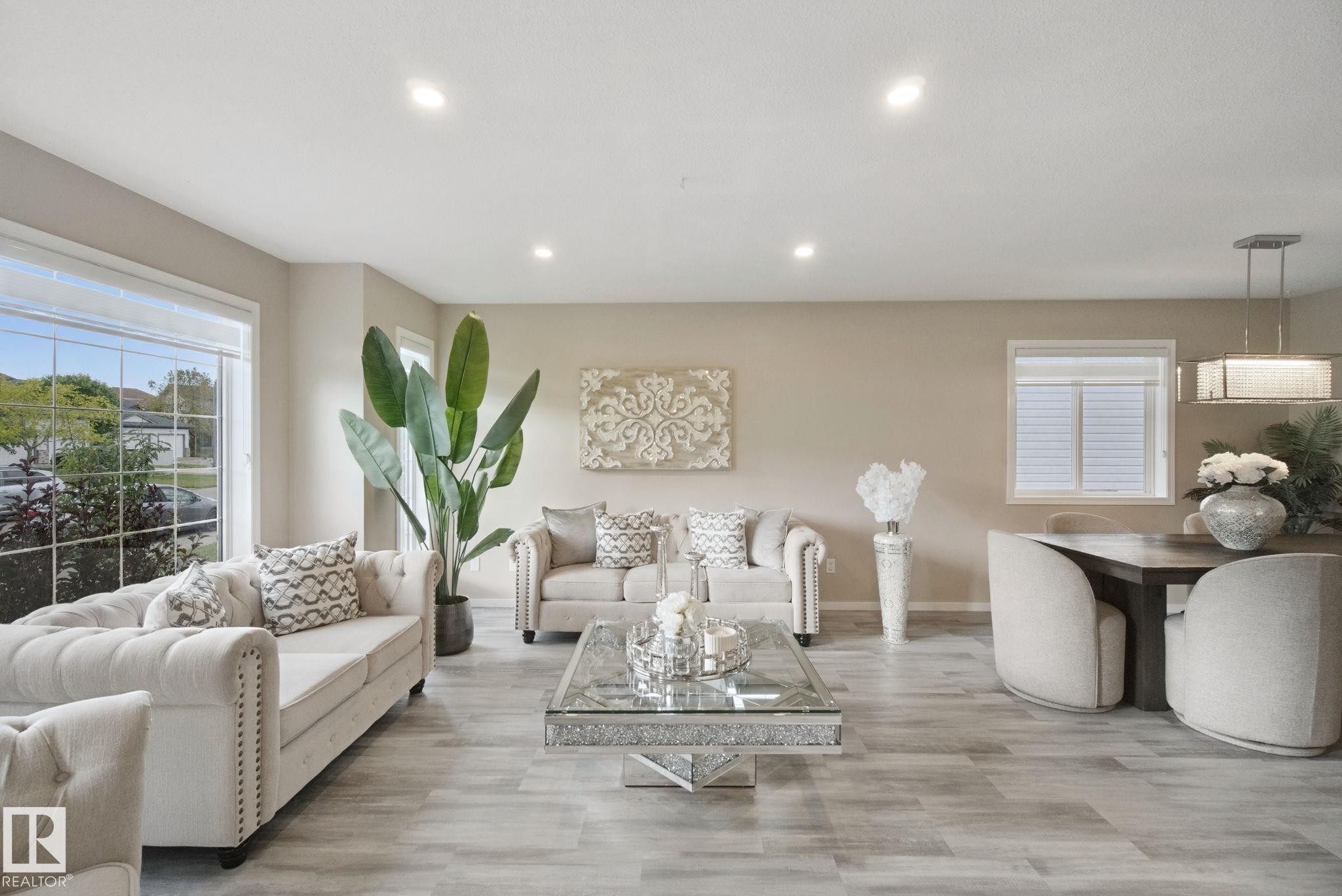 Wood-finish flooring throughout, recessed ceiling lights, large picture window, a secondary window with blinds, and a modern rectangular chandelier - 13912 156 Avenue Nw, Edmonton, AB