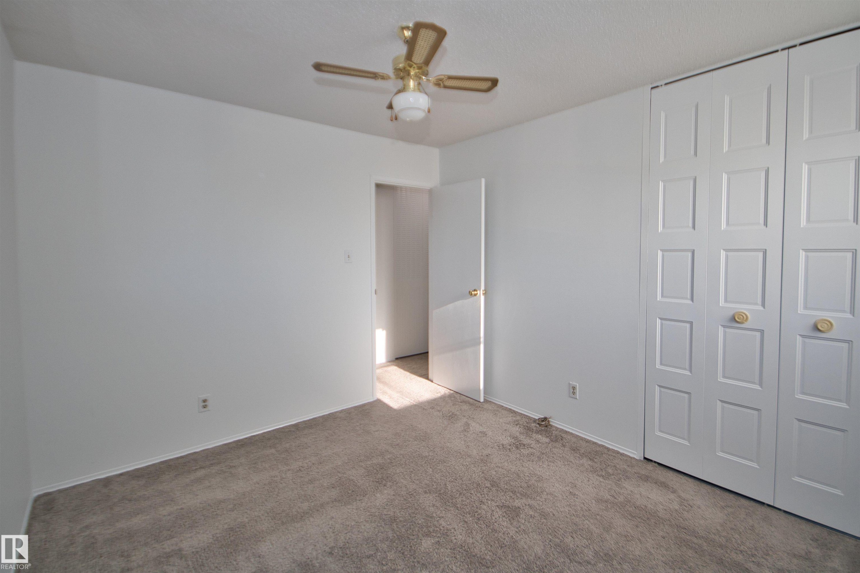 Carpeted flooring, white walls, ceiling fan, and bi-fold closet doors - 7743 37 Avenue Nw, Edmonton, AB