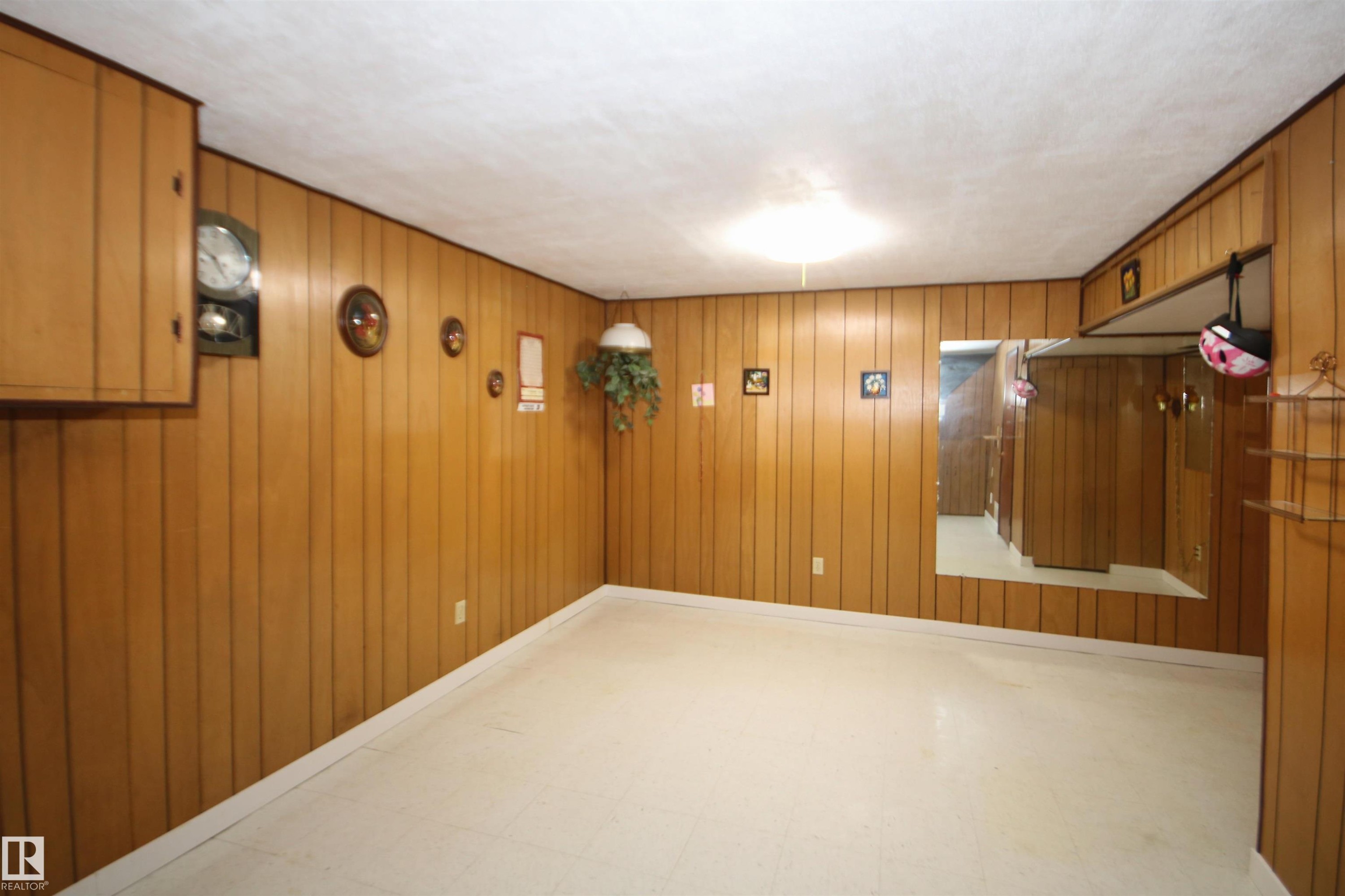 Wood-paneled walls with built-in cabinetry and a large wall mirror - 7743 37 Avenue Nw, Edmonton, AB