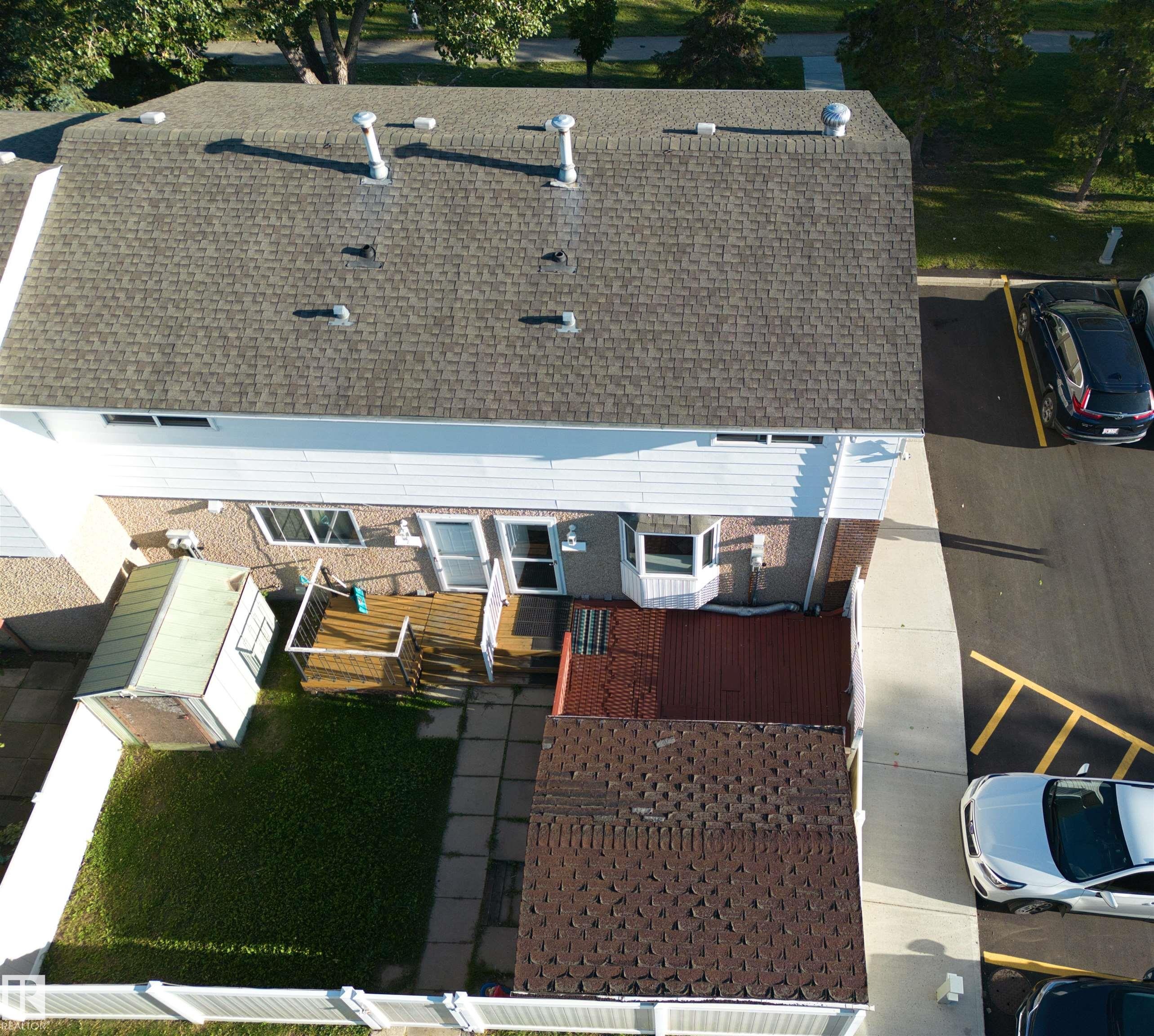 Asphalt shingle roofing, white vinyl siding, rear deck, concrete patio, and a fenced yard - 7743 37 Avenue Nw, Edmonton, AB
