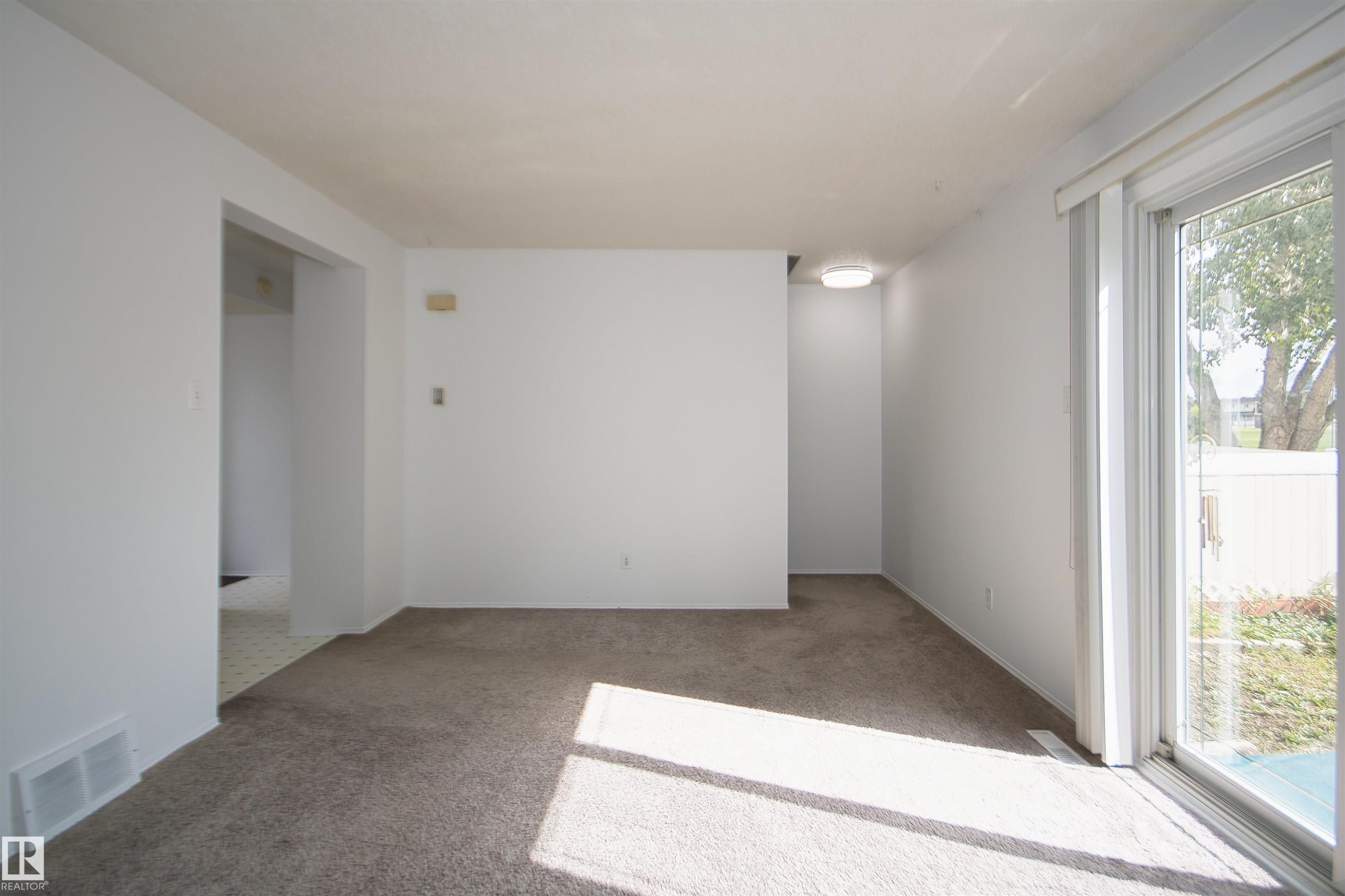 Neutral-toned carpeted flooring, white painted walls, and a sliding glass door - 7743 37 Avenue Nw, Edmonton, AB
