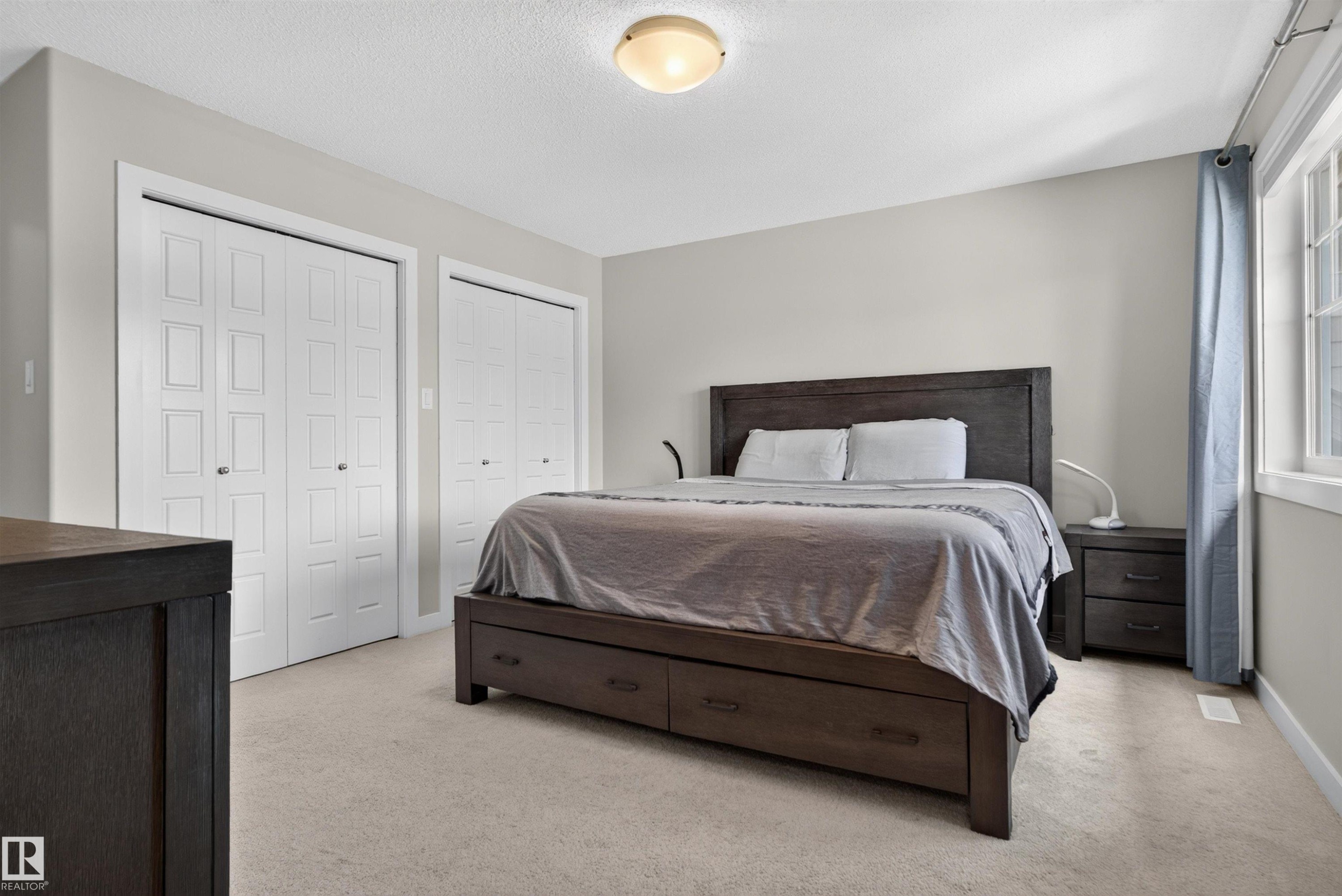 Recessed lighting, light neutral wall color, window with white trim, light-toned carpet, and multiple bi-fold closet doors - 319 Desrochers Boulevard Sw, Edmonton, AB