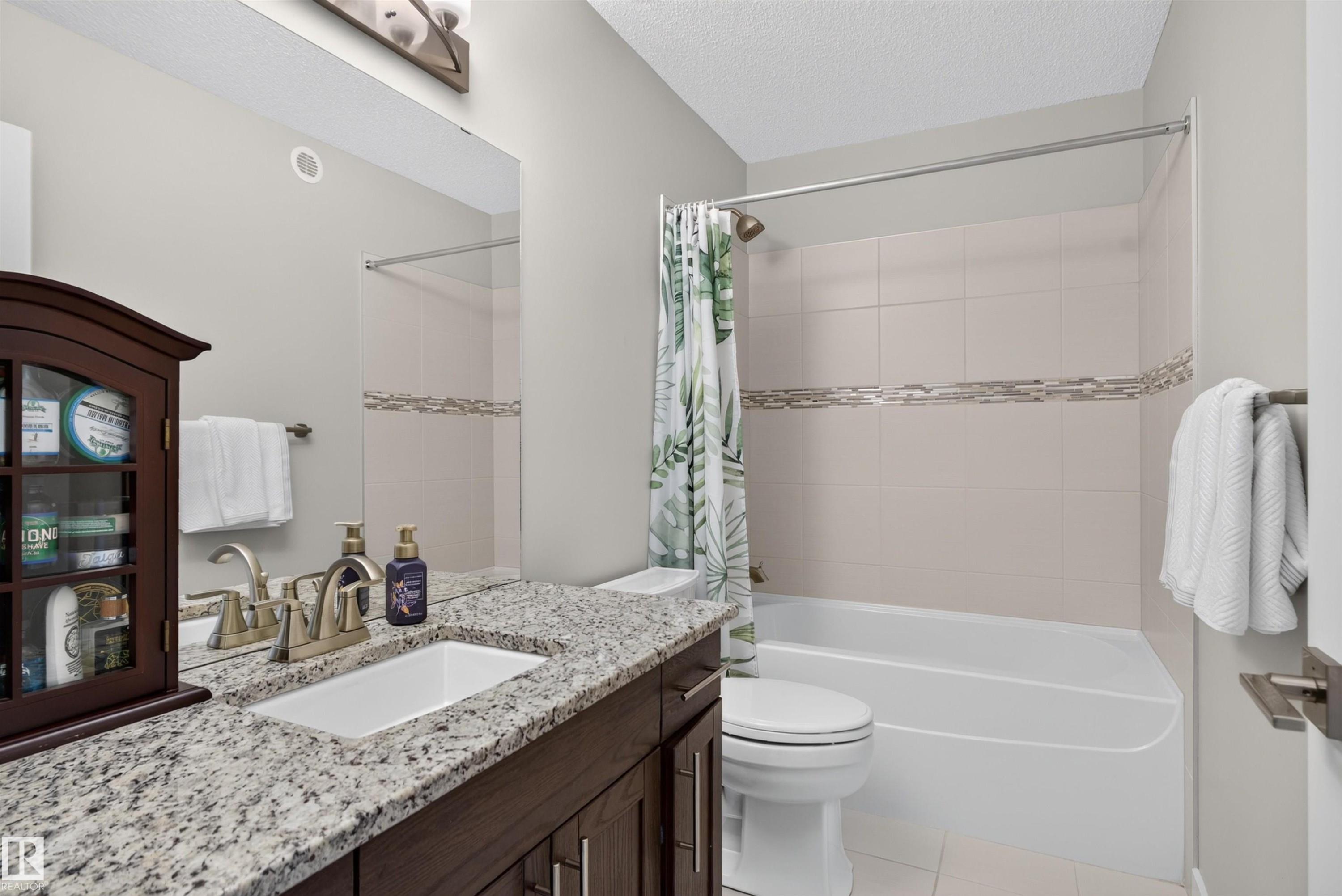 Granite countertop vanity with an undermount sink, brushed nickel faucet, and wood-finish cabinetry - 319 Desrochers Boulevard Sw, Edmonton, AB