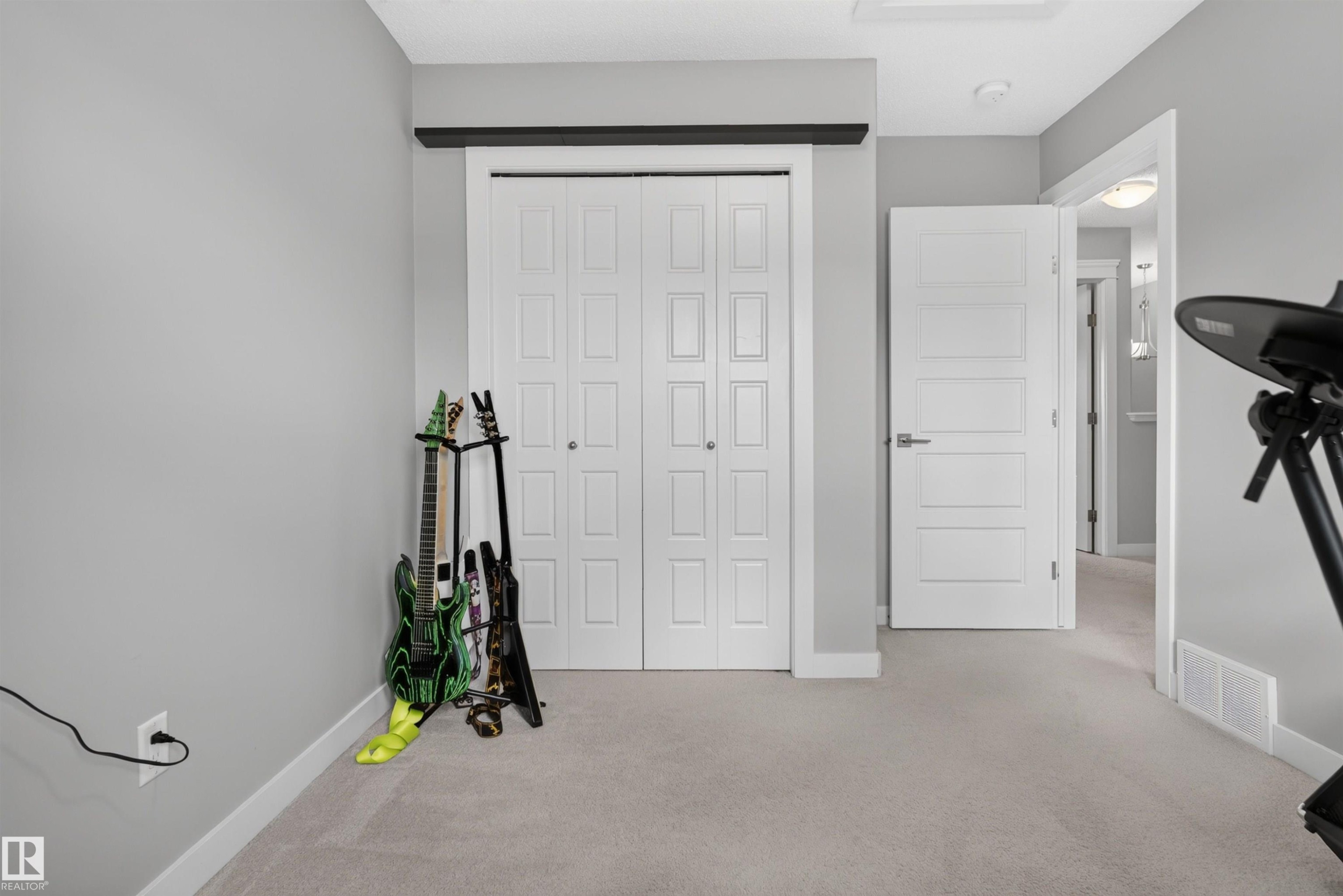 Neutral wall color, light-toned carpeting, panel bi-fold closet doors, and a paneled interior door with modern hardware - 319 Desrochers Boulevard Sw, Edmonton, AB