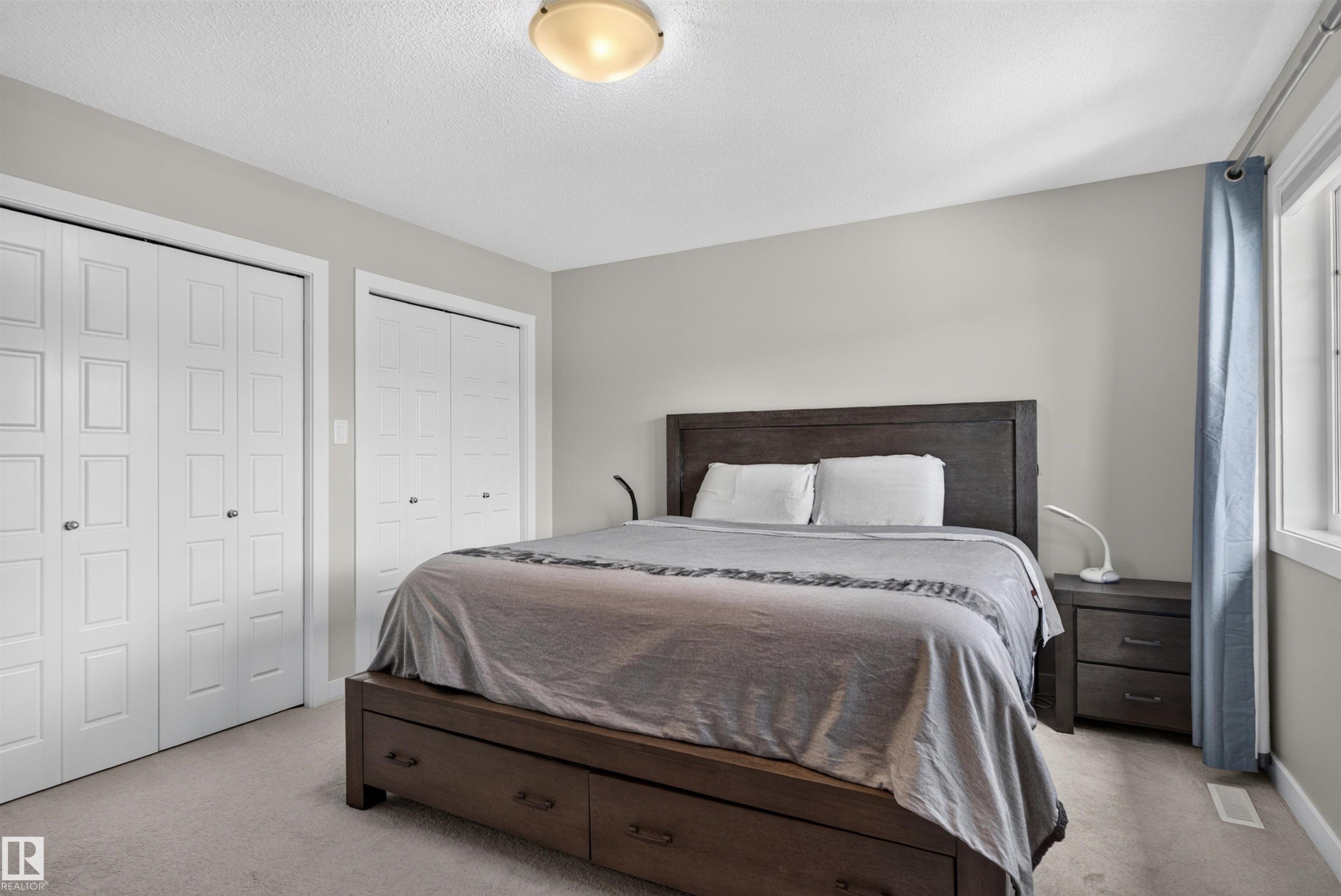 Two sets of bi-fold closet doors, wall-to-wall carpeting, and a window with curtain rod - 319 Desrochers Boulevard Sw, Edmonton, AB