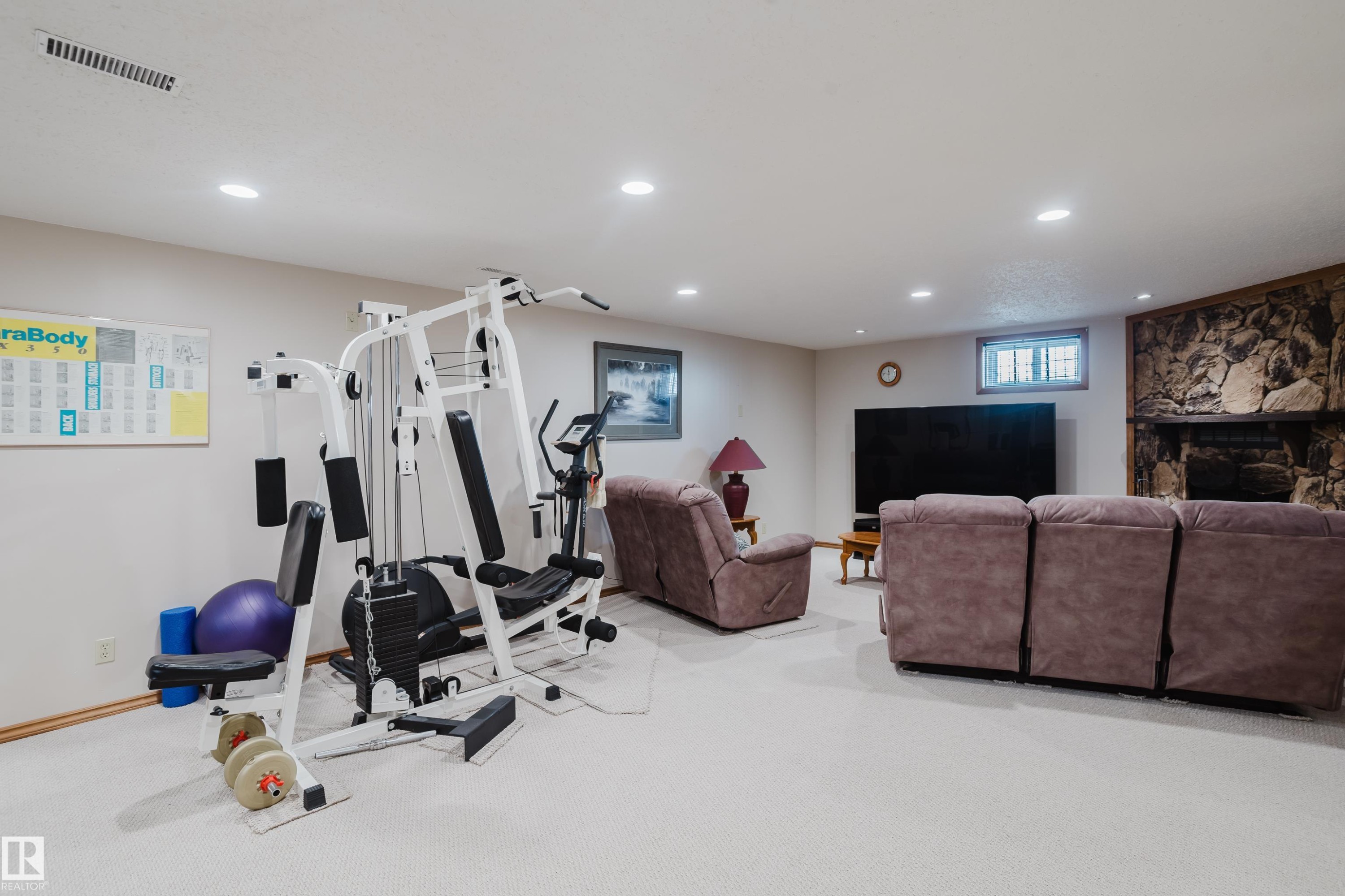 Recessed lighting, light-toned carpeting, a stone-clad fireplace, and a large television alcove - 10924 35A Avenue Nw, Edmonton, AB