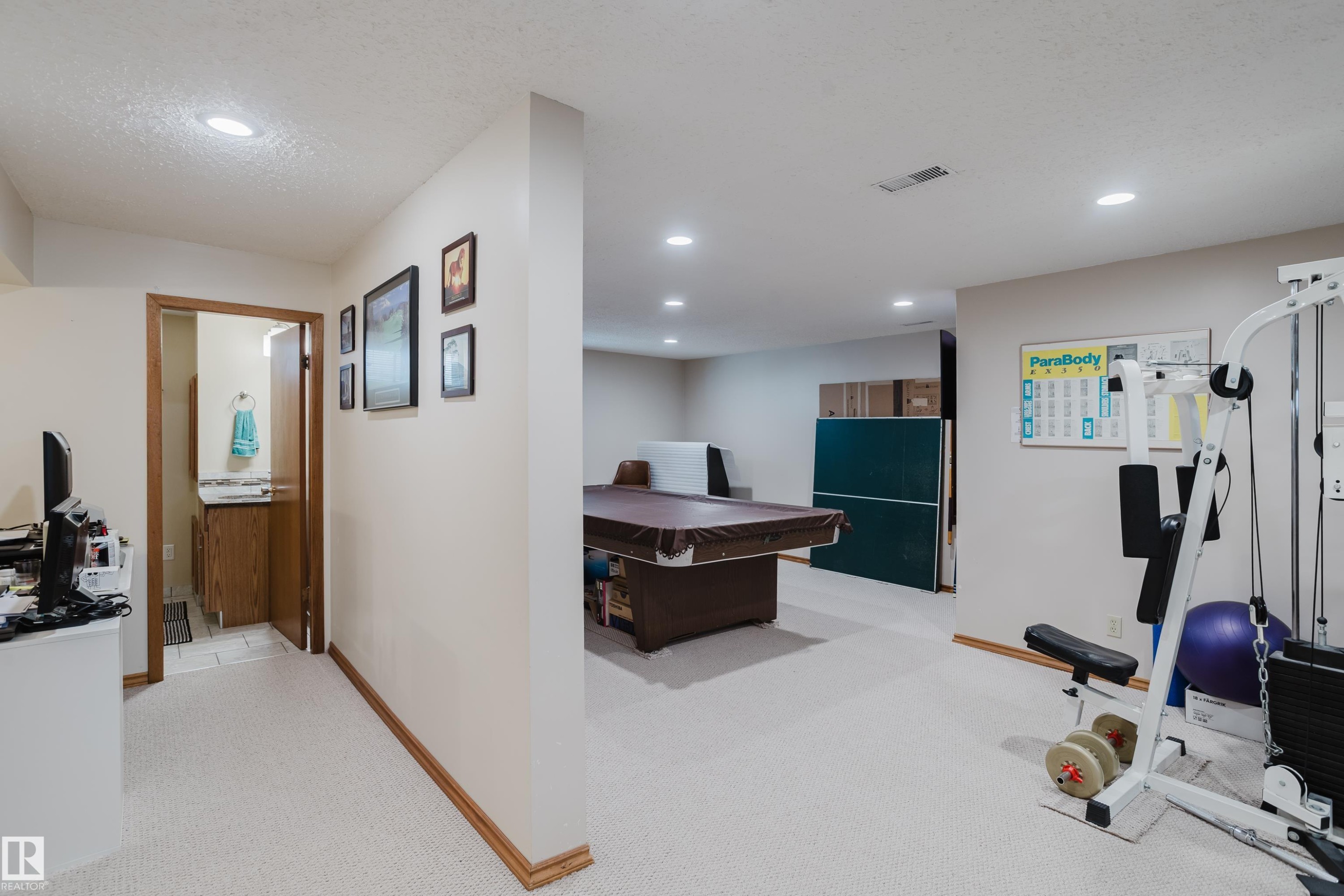 Recessed ceiling lighting, light-toned carpeting, wood trim, and an adjacent bathroom with a wood vanity - 10924 35A Avenue Nw, Edmonton, AB