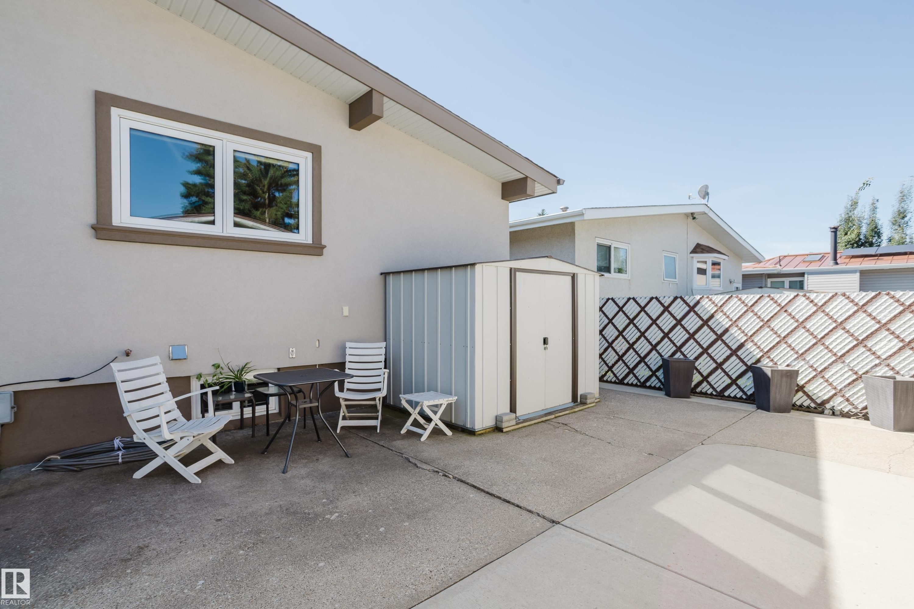 Poured concrete patio with a metal storage shed and a decorative lattice fence - 10924 35A Avenue Nw, Edmonton, AB