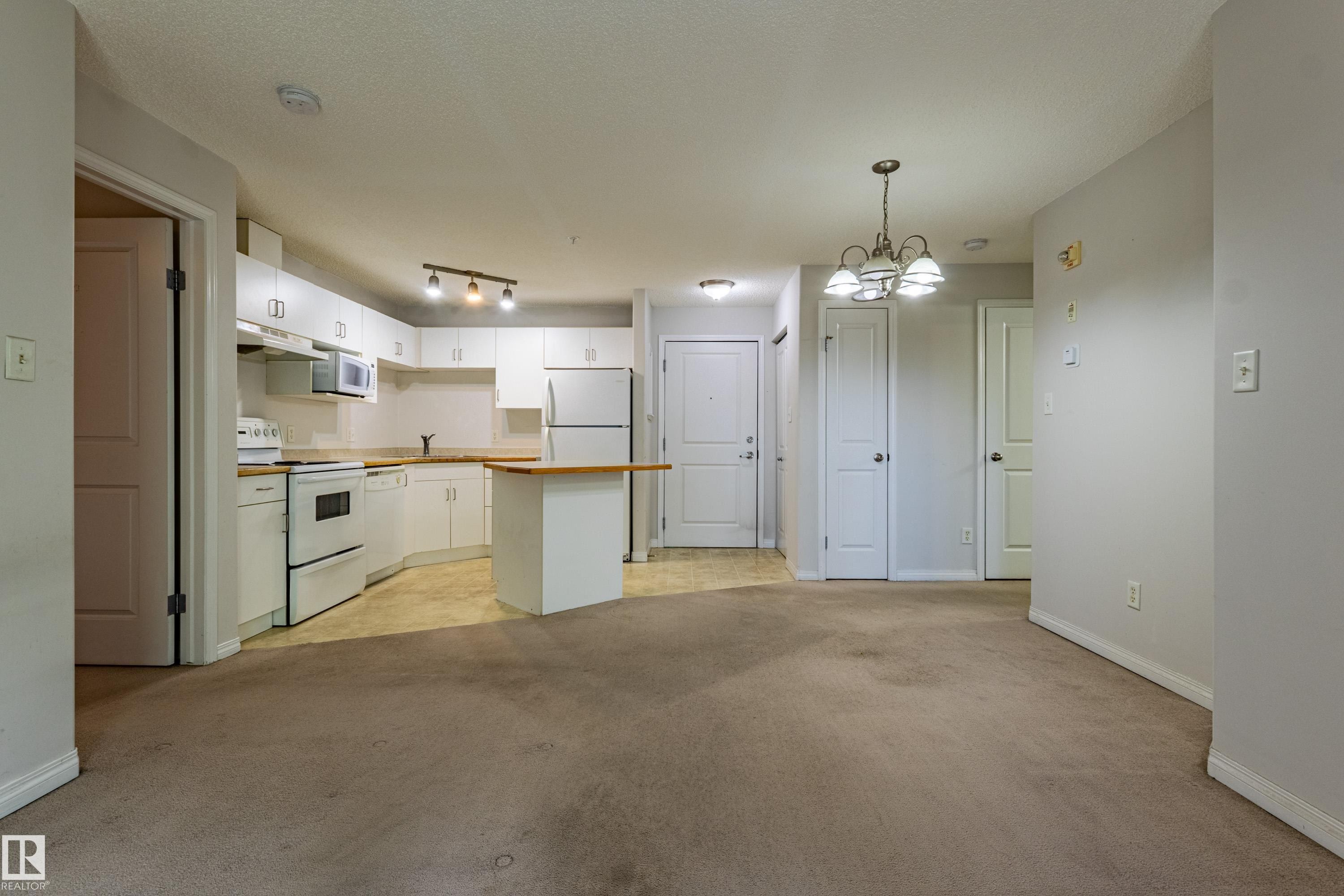 Kitchen with white cabinetry, a built-in microwave, and a breakfast bar - #316 11325 83 St Nw, Edmonton, AB
