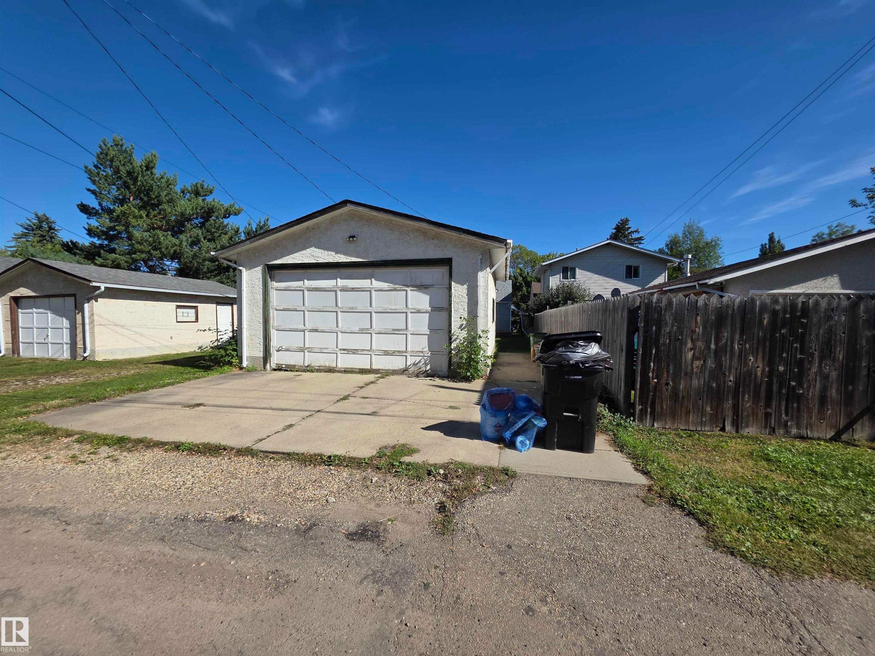 Detached garage with a paneled door, concrete driveway, and stucco exterior - 10438 147 Street Nw, Edmonton, AB